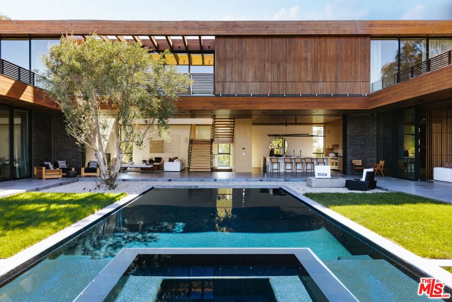 This stunning new architectural gem, designed by the acclaimed Noah Walker, sets a new standard for luxury living. Nestled behind the prestigious gates of Oak Pass Road in Beverly Hills, this ultra-private estate offers a rare combination of seclusion and grandeur. Spanning across an expansive floor plan, the home features 7 spacious bedrooms and 9 lavish bathrooms, perfect for both intimate living and large-scale entertaining. The journey begins through an impressive glass pivot door, greeted by a 10-foot indoor greenery wall, elegant brick-clad columns, and soaring hardwood ceilings. The state-of-the-art kitchen is a chef's dream, with dual marble islands, oak cabinetry, top-of-the-line Wolf and Subzero appliances, and two Miele coffee makers. The kitchen seamlessly flows into the dramatic two-story living area, complete with a custom floating staircase that connects all levels of this architectural wonder. Designed to blend indoor and outdoor living, the home boasts 50-foot Fleetwood pocket doors that open to the meticulously landscaped grounds, featuring a zero-edge pool and spa, an outdoor kitchen, fire pit, olive trees, and multiple lounging areas all set against breathtaking panoramic views. First-class amenities include a private movie theater, fully equipped gym, Himalayan salt sauna, dual steam showers, a temperature-controlled wine display, three private balconies, and a Crestron smart home system. The motor-court, lined with mature oak trees, adds the finishing touch to this one-of-a-kind estate. This extraordinary residence offers an unmatched level of sophistication, set in one of the most exclusive locations in Beverly Hills. An unparalleled opportunity for those seeking ultimate luxury.