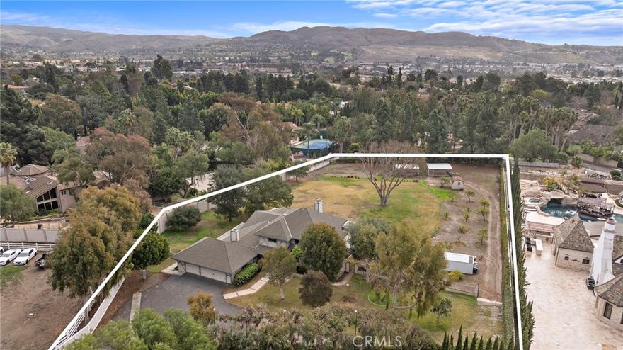 Discover your very own ranch-inspired hideaway at the end of a long, private road in one of San Juan Capistrano’s most exclusive neighborhoods west of I-5. Embracing more than 1.75 acres of flat open land, this rare fully gated and fenced estate is paradise for those seeking a relaxed equestrian-oriented lifestyle that feels far away from it all but is surprisingly close to beaches and city conveniences. Mature shade trees lend charm to the enormous homesite, where ample room is available for realizing your dreams of an equestrian oasis complete with a luxurious custom home, a barn, pen, turnouts and an arena. There is even room to add a lavish resort pool, spa and outdoor kitchen. Only your imagination is the limit. Architectural renderings of proposed building plans are included, and the owner has completed a topography map, survey and soil testing. Award-winning schools are close by, and San Juan Capistrano’s vibrant downtown, with its popular shops, restaurants and historic mission, is moments away. Explore Dana Point’s famous harbor, which is currently being revitalized, and spend a day with friends and loved ones on the sands of Doheny Beach. This outstanding property offers direct access to more than 60 miles of scenic riding trails that lead to Salt Creek Beach, Los Rios Historic District, San Juan Hills Golf Course and Trabuco Creek Trail. Ready to be further improved with your personal touch or completely replaced, a beautiful Tudor-style residence greets all upon arrival, setting the scene for preferred living and entertaining. Enjoy the elegance of a double-height foyer with dramatic multi-tiered staircase, formal living and dining rooms that open to a wraparound veranda with backyard views, four spacious bedrooms and three- and one-half baths. Approximately 3,996 square feet, the two-story design continues to impress with a fireplace-warmed family room with deck access that flows effortlessly to a generous remodeled kitchen with white Shaker cabinetry, quartz countertops, full tile backsplash, farmhouse sink, and stainless steel appliances including a double oven and six-burner cooktop. The main level showcases a luxurious primary suite with a handsome brick fireplace and raised hearth, sitting area, deck and ensuite bath. An attached three-car garage and dual RV access are featured, and the motorcourt generously accommodates guest parking.