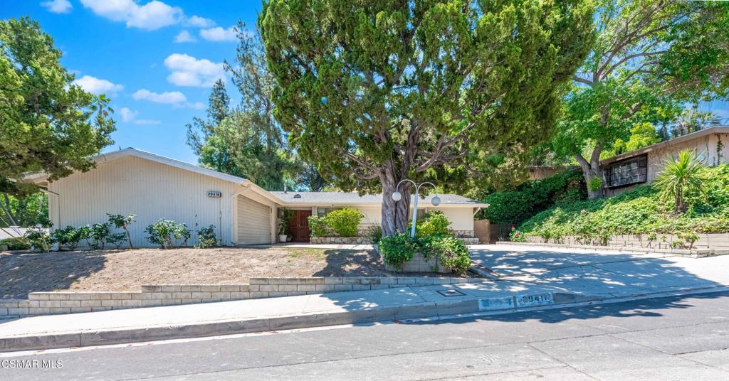 Tucked away on a quiet street in Woodland Hills, this charming 3-bedroom, 3-bathroom home offers 1,800 sq ft of comfortable living space on an expansive 14,263 sq ft lot. A private driveway and mature landscaping welcome you to this single-story residence with classic mid-century appeal.Step inside to find a spacious living room anchored by a striking floor-to-ceiling stone fireplace and large windows that flood the space with natural light. The adjacent dining area features glass sliders that open to a covered patio--ideal for seamless indoor-outdoor entertaining.The kitchen maintains its warm, original character with solid wood cabinetry, tiled countertops, and a cozy breakfast nook that opens into a light-filled sitting area. Throughout the home, you'll find charming vintage details, vaulted ceilings, and a layout that invites both comfort and functionality.The backyard is a tranquil escape, complete with lush, mature landscaping, a spacious covered patio, and a terraced hillside offering privacy and potential for creative outdoor expansion.Whether you're looking to move right in or reimagine the space with your own updates, this well-maintained property is full of opportunity in one of the most desirable neighborhoods of the Valley.
