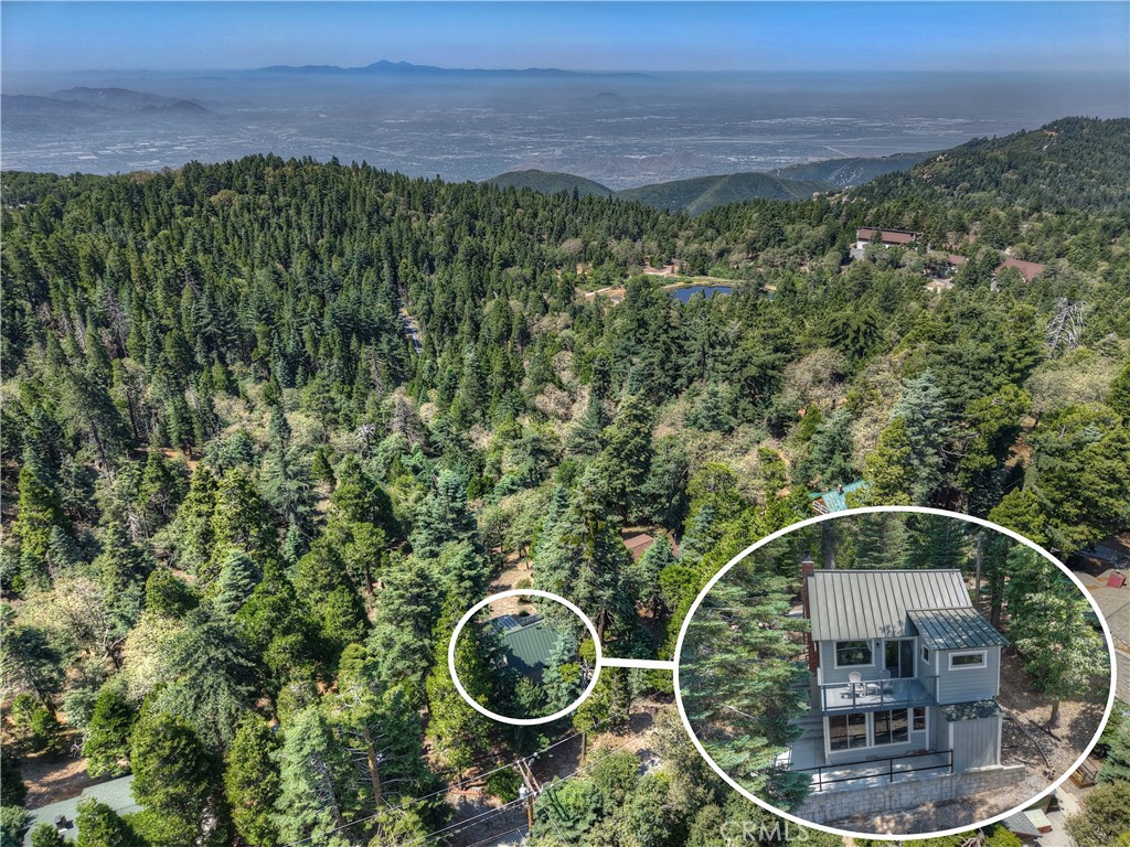 Perched at a true mile high, this cabin borders national forest and offers panoramic views that sweep from towering pines to twinkling city lights far below. Located in the desirable neighborhood of Strawberry Flats, sits this nearly 100 year old cabin that has been Lovingly updated just enough, without taking all of the charm away. The owners have created a truly enchanting & unique living space they have enjoyed for many years with family & friends. The main floor offers the cozy living area with warm wood walls & beamed ceilings. Vintage rock fireplace with efficient gas insert makes this the ideal spot to settle in & relax. Just adjacent is the small but efficient kitchen space complete with modern yet vintage looking appliances with the perfect splash of color. There is also a 3/4 bath on this level & a sun filled sleeping area. Upstairs there is a sleeping loft which makes a great space for extra guests. From the living room you can access the weatherproof glass enclosed deck area with the best 4th of July fireworks view, or just capturing the city & far valley views anytime. The lower floor which can be accessed either inside the house our outside around the side features a spacious flex room! This can be used for sleeping, gathering, movie watching or whatever you may need. There is a separate heater on this level for those chilly winter evenings. From this room you can access what the owners call the "tea room" which has a beautiful view out to the forested area surroundings & the valley lights below. This is the perfect place to stay warm & cozy while watching snowflakes drift down. This room also has access to an additional 1/2 bath & laundry & also to the beautiful outdoor concrete patio area. This enchanting cabin has great elbow room & a feeling of seclusion yet you are just 7 minutes to Blue Jay, 10 minutes to Lake Arrowhead, 5 minutes to Lake Gregory & 20 minutes to San Bernardino. The best of all worlds is right here and ready for you to embrace!