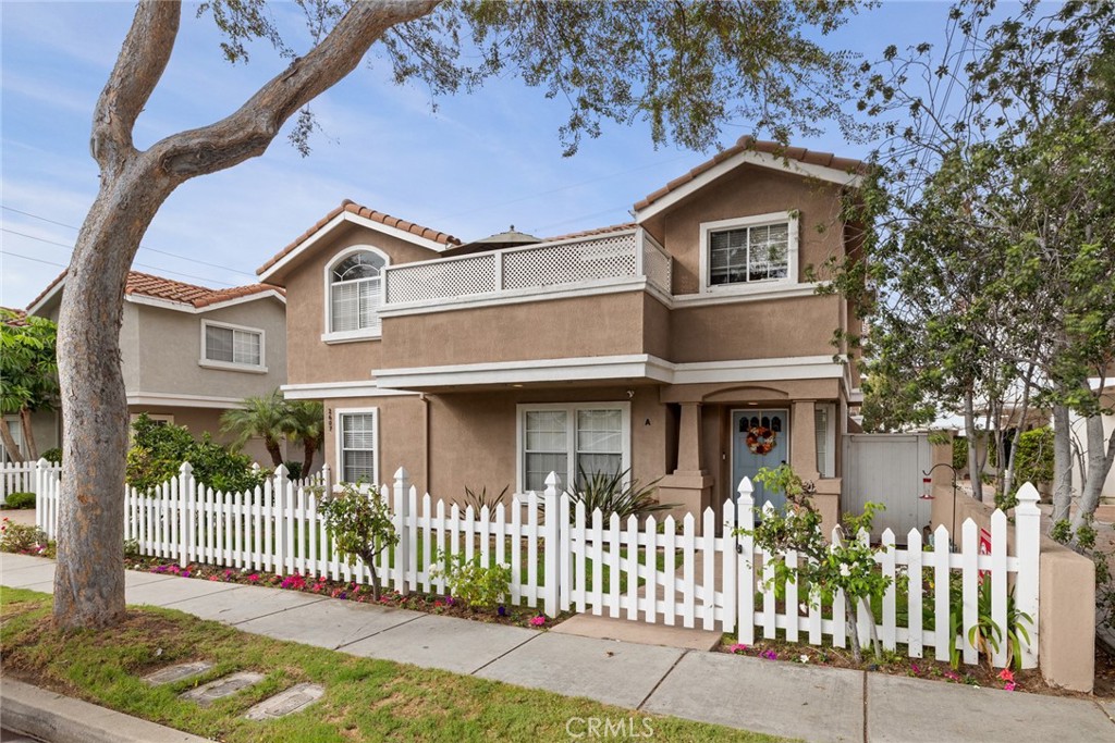 An enclosed front yard with a white picket fence, colorful roses, and even a sweet Cara Cara orange tree sets the stage for this sunny south-facing front-unit townhome. This welcoming outdoor space is perfect for morning coffee, tending your garden, or simply enjoying the neighborhood charm. Step inside through the formal stone-tiled entry and discover a spacious, flexible floorplan designed for both comfort and convenience. Two bedrooms and a full bathroom are located downstairs, ideal for guests, extended family, or a quiet home office. Upstairs, the main living areas open up dramatically with soaring ceilings, a light stone fireplace focal point, and expansive windows that invite in natural sunlight throughout the day. The heart of the home is the generous living room, seamlessly connected to the dining area and kitchen by newer wide-plank oak hardwood flooring. Entertain with ease here, whether hosting the holidays in the dining room, enjoying casual meals at the breakfast bar, or stepping out to one of two balconies for fresh air and relaxation. The open flow makes it a breeze to gather with loved ones, while the kitchen is thoughtfully equipped with stainless steel appliances, granite counters and backsplash, light wood cabinetry, and a pantry for convenient storage. A convenient half bath off the hall serves the living and entertaining areas, ensuring ease for both residents and visitors. Beyond, your spacious primary suite awaits, complete with a vaulted ceiling, walk-in closet, and a spa-style bathroom featuring dual sinks, a jetted tub, a separate shower, and a private water closet. Adjacent to the primary suite is a rare 4th bedroom upstairs perfect for a nursery, home office, or cozy den, adding valuable flexibility. Downstairs, two additional bedrooms share a full bathroom and are located near the in-home laundry, making everyday routines seamless. Additional highlights include storage under the stairs, central air conditioning, multiple ceiling fans, and a two-car attached garage with direct access and even more storage space. This intimate three-unit community is well maintained and recently refreshed with exterior paint for a crisp sense of arrival. Ideally located near top-rated schools, parks, shops, restaurants, the beach, and freeway access. This residence offers the perfect mix of coastal lifestyle, daily convenience, and the benefit of four bedrooms, all at an exceptional value in the heart of the South Bay, ready to welcome you home.