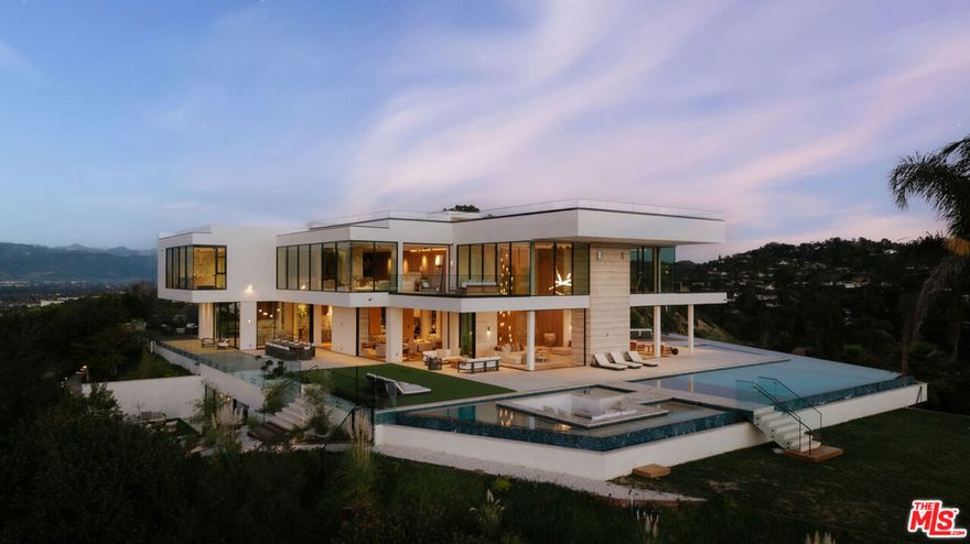 Set behind a secluded private gate on nearly two acres, 16187 Royal Oak Rd stands as Encino's crown jewel - a modern estate where striking architecture and sweeping canyon and city views define every moment. The home immediately impresses with its clean lines, soaring ceilings, and floor-to-ceiling glass that opens the interior to the surrounding landscape. A grand pivot door leads into open living spaces designed for both ease and impact, centered around a chef's kitchen that flows seamlessly into the dining and lounge areas. Outside, an infinity pool, spa, and multiple terraces create a private resort-like setting framed by lush greenery. The estate features 8 bedroom suites and 11 baths, plus standout amenities including a state-of-the-art theater, wine cellar, gym, and spa. The primary suite offers its own retreat with a private terrace and a spa-inspired bath. 16187 Royal Oak Rd delivers the rare combination of design, scale and setting - an exceptional estate that defines elevated living.