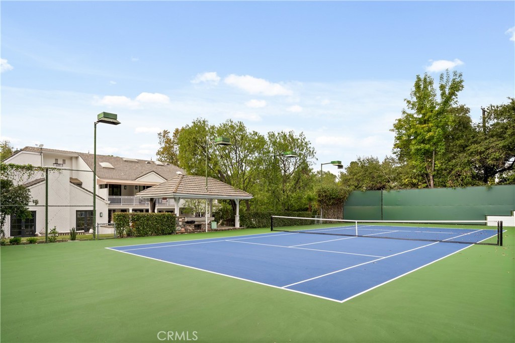 Located in the heart of prime Encino, this exceptional turnkey tennis court estate offers over nearly an acre of luxurious living. The meticulously designed, fully furnished 6,661 sq ft home strikes the perfect balance between privacy and elegance. High ceilings throughout create an airy, open ambiance, while the thoughtful layout ensures a seamless flow between spaces. The residence boasts 6 spacious bedrooms, 7 bathrooms, a formal living room with custom built-ins, a grand family room with soaring pitched ceilings, a dedicated laundry room, and a chef’s kitchen that opens to the poolside. Step outside to discover an expansive custom pool with a cascading waterfall, beautifully framed by lush landscaping. The estate also features a private tennis court with a charming gazebo-covered seating area, a fire pit, and plenty of room for entertaining. With its coveted location and undeniable appeal, this home is the epitome of sophisticated Southern California living.