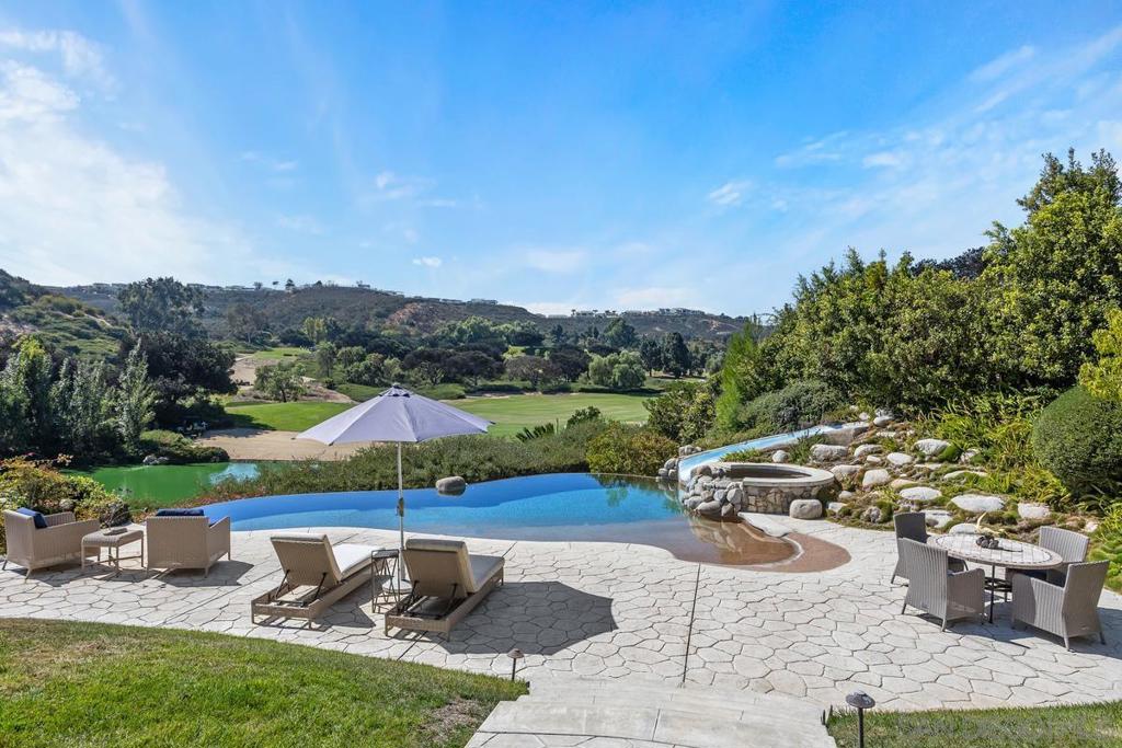 Welcome to 6185 Clubhouse Drive, an exquisite French Country custom estate nestled behind the exclusive gates of the Del Mar Country Club. This home is perfectly positioned to capture breathtaking views of the 9th fairway, offering a rare blend of luxury and privacy on a premiere .7AC view-filled homesite. Spanning over 6,131sf, this elegant residence is thoughtfully designed to live like a single level, featuring a sumptuous primary suite and two additional en-suite bedrooms on the main floor. Upstairs, discover a versatile apartment-style en-suite bedroom with a bonus room and private balcony, accessible via a separate stairwell—ideal for guests or extended stays. The home's two formal offices, one on each level, provide inspiring views and flexible spaces for work or creative pursuits. The gourmet kitchen is a chef's dream, boasting a large island and dual walk-in pantries. Step outside to your private resort-style backyard, where an outdoor kitchen and a saltwater pool with a slide await. The spa and expansive patio area offer an oasis of relaxation, all set against a backdrop of 180-degree panoramic verdant views. The property's solar system is fully paid for, adding energy efficiency. Additional amenities include a pet shampoo station in the large laundryroom, separate his and hers dressing areas in the primary bath suite, large Koi fish pond and separate sun room with a fireplace off the kitchen to relax with views while enjoying morning coffee.