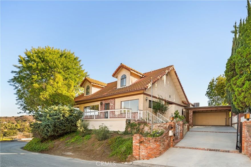 Nestled into the hillside on a quiet street in Woodland Hills, this gated corner lot property offers breathtaking views of the Valley and surrounding hills. Step inside to a spacious living room that's flooded with natural light, accentuating the warmth of the original hardwood floors. At the heart of the home lies a designer chef’s kitchen, featuring high-end JennAir appliances, gorgeous marble countertops, a hidden walk-in pantry and inviting breakfast nook. Two sets of French doors lead out to a private covered patio with an in-ground spa, the perfect place to relax and soak in the unobstructed views. This home consists of four generously sized bedrooms (two on each level) and three full bathrooms (two on the main level and one upstairs). Each bedroom has its own walk-in closet, ensuring ample storage throughout. Additional highlights include a laundry closet, EV charger, wrap around front patio and oversized two-car garage with an overhang for additional covered parking. Ideally located south of the Boulevard, enjoy easy access to local shops/restaurants, the Woodland Hills Country Club and so much more.