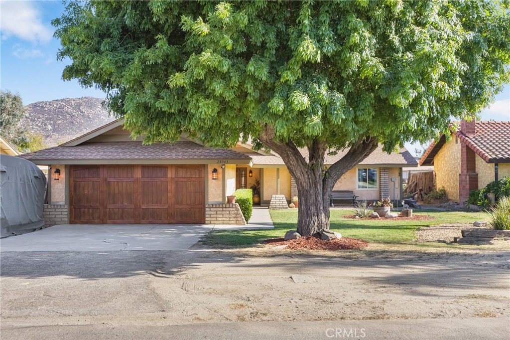 Welcome to 28943 Gifford Avenue—where custom craftsmanship, comfort, and convenience meet in the heart of East Moreno Valley. This beautifully remodeled Ranch-Style home offers 4 bedrooms, 2 bathrooms, and 1,448 square feet of living space on a spacious 8,276-square-foot lot. From the moment you arrive, you’ll be captivated by its charm and curb appeal, highlighted by a newly installed Mediterranean Knotty Alder front door and matching garage door that set the tone for the warmth and character found inside. Step into the inviting entryway, where a striking custom mosaic tile centerpiece and exposed oak wood ceiling beams create a rich, rustic ambiance. The living room features real hardwood flooring and a stunning Spanish-style fireplace, while timeless wood baseboards and elegant fixtures tie every detail together. The heart of the home is the chef’s kitchen, complete with Mesquite wood cabinetry, travertine floors, and a beautifully designed overhead stove façade that blends function and style. Both bathrooms showcase thoughtful upgrades, including a custom Spanish-style vanity in the guest bath that adds an old-world touch. Energy-efficient features include dual-pane windows, an on-demand tankless water heater, a new electrical panel, dual QuietCool attic fans, and an Ecobee smart thermostat with Siri voice control and mobile app access. Outdoors, enjoy easy maintenance with an ORBIT 6-zone irrigation and drip system, also remotely controlled by app. For peace of mind, a 4-camera security system with mobile monitoring is also included. Perfectly positioned in a tranquil neighborhood, this home is just minutes from the newly revamped Rancho Del Sol Golf Club, Lake Perris for boating and scenic bike trails, local schools, equestrian facilities, hospitals, shopping centers, and the upcoming World Logistics Center. Whether you’re relaxing inside or exploring nearby amenities, this one-of-a-kind home offers both serenity and accessibility—with no HOA to worry about.