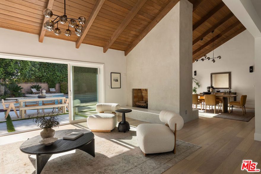 Stunning Mid-Century Charles DuBois Architectural with Pool in Prime Woodland Hills. Located on a desirable corner lot in one of the most sought-after areas of Woodland Hills, this impeccably remodeled Mid-Century Charles DuBois home offers over 3,000 sq ft of thoughtfully designed living space with 4 bedrooms and 3.5 bathrooms. Step through a custom oversized front door into a sun-drenched, open-concept interior featuring soaring ceilings with exposed beams, wide-plank white oak floors, and a dramatic Venetian plaster double-sided fireplace separating the formal living and dining areas. The chef's kitchen is a showpiece designed for both entertaining and everyday living. Highlights include a striking waterfall island, sleek wood and glossy white cabinetry, gold vein Calacatta countertops, and top-tier appliances including a panel-covered Fisher & Paykel fridge, Miele dishwasher, Frigidaire double oven, and Thor gas range. No detail was overlooked in this one-of-a-kind renovation: designer light fixtures, floating vanities, custom accent walls, solid extra-tall wood doors, and premium tile and finish selections throughout. The luxurious primary suite features cathedral ceilings with a central beam, a spa-like bath with a freestanding tub, floating double vanity, oversized walk-in shower, and a massive custom walk-in closet. Additional highlights include a spacious laundry room and pantry with smart controls, and a separate en-suite bedroom located on the opposite wing of the home ideal for guests or multigenerational living. Step outside to a private resort-like entertainer's backyard with newly designed hardscape, lush modern landscaping, and a large sparkling pool. Major upgrades include newer roof, dual HVAC systems, updated electrical panel, tankless water heater, recessed lighting, CAT wiring, plumbing, all new pool equipment and solar panels for the house which offers a huge savings. A detached garage with a private side entrance offers excellent ADU potential. Ideally located near top-rated charter schools, Bristol Farms, Calabasas Commons, Topanga Village, and the beloved local Farmer's Market, with quick access to the 101 freeway. The best value in Woodland Hills based on quality remodel, lot size, privacy and location.