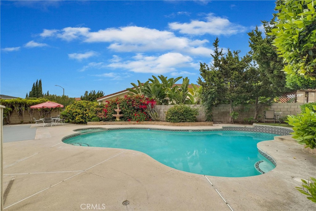 Welcome to this Charming and Lovely pool home offering comfortable living, tucked away at the end of a quiet cul-de-sac in a prime neighborhood near Disneyland. Impeccably maintained and move-in ready, this spacious home features a light-filled, open layout with 5 bedrooms, a generous loft, and 3 bathrooms. Step through the double-door entry into the sunken formal living room with vaulted ceilings and a charming river rock fireplace—an inviting space to unwind. Host memorable dinners in the elegant formal dining room, perfectly suited for entertaining. The kitchen is a chef’s delight, complete with a built-in breakfast nook island, stainless steel appliances, quartz countertops, and a picturesque view of the backyard oasis. Adjacent is the cozy family room with large sliding glass doors that provide seamless indoor-outdoor flow. Retreat to the serene primary suite conveniently located on the main level, featuring a walk-in closet and ensuite bath with dual vanities and a walk-in shower. The tow other bedrooms are also located downstairs—ideal for multigenerational living, guest accommodations, or home office flexibility. Upstairs, you’ll find the remaining 2 bedrooms and a versatile loft, perfect for a play area or creative space. Enjoy the ultimate outdoor lifestyle with a sparkling pool and spa surrounded by mature trees, offering both privacy and tranquility. The enclosed patio extends your living space with direct access from the living room—perfect for enjoyment. Additional features include a Two-car finished garage with built-in cabinets , newer laminate wood flooring throughout the first floor, updated dual-pane windows and sliding doors, plantation shutters, central air and heat, water Purifier, ceiling fans, and more. Centrally located near local schools, Modjeska Park, shopping, and dining—this turnkey home has it all. Don’t miss your chance to make it yours!