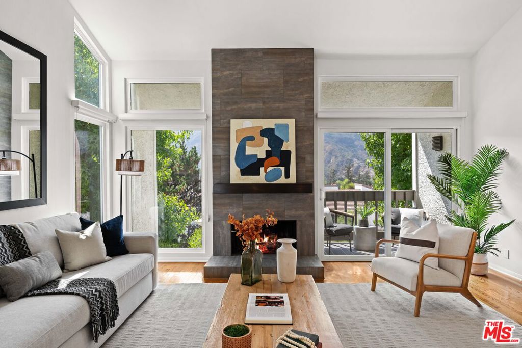 Tranquil Townhome with Sweeping Mountain Views! Nestled amid the Santa Monica Mountains, this spacious 2-bedroom, 2.5-bath townhome invites you to experience Pacific Palisades living at its finest. Sun-drenched interiors flow seamlessly to outdoor terraces, allowing you to savor treetop and mountain views from nearly every room. Upstairs, an open living and dining area with soaring ceilings and a cozy fireplace opens to a terrace framed by lush greenery and panoramic vistas. The eat-in kitchen combines style and functionality, perfect for morning coffee while overlooking the tranquil scenery, or hosting gatherings bathed in natural light. Downstairs, the primary suite and second bedroom share a beautiful wrap-around patio, offering sweeping mountain and treetop views. The primary suite features a walk-in closet and en-suite bath, creating a serene retreat. The second bedroom includes a built-in office area, ideal for remote work or study, and an adjacent full bathroom. Additional highlights include newly carpeted bedrooms, generous storage, and an attached two-car garage with laundry. Residents enjoy resort-style amenities: pool, spa, sauna, fitness room, and tennis courts, all set within beautifully landscaped grounds overlooking verdant hills. Located in the peaceful Palisades Highlands yet minutes from the Village, hiking trails, and the beach, this home blends natural beauty, convenience, and a lifestyle of calm sophistication. Experience mountain-view living in the heart of the Palisades-schedule your private tour today.