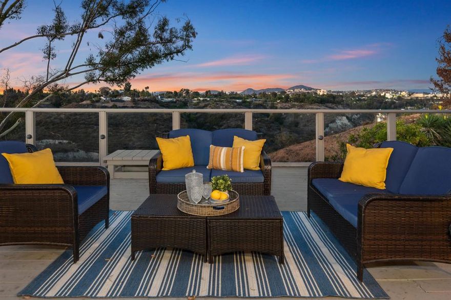 Nestled on a canyon lot, this airy and inviting Talmadge home offers panoramic views and beautifully landscaped front yard with excellent curb appeal. Step through the charming stained-glass front door into a formal entry, where your gaze is immediately drawn to the sweeping canyon beyond. Hardwood floors and warm wood trim flow throughout the home, complementing the cozy fireplace in the living room. The spacious primary suite features a recently remodeled bathroom blending comfort with modern style...  Lovely kitchen offers abundant cupboard and counter space and eating bar, and opens to a cheerful breakfast room with a large picture window framing the canyon view. Sliding glass doors from the living room lead to an expansive deck, with a sleek plexiglass view through railing, perfect for entertaining. Additional highlights include a direct-entry garage (with Tesla wall charger) and thoughtful layout, ideal for both relaxed family living and lively gatherings.