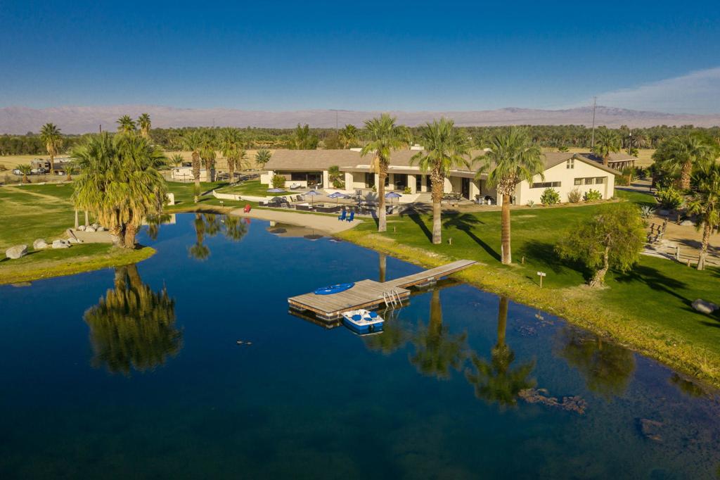 Very Rare Offering: Premier Venue situated on 38+ acres in the heart of Vista Santa Rosa. Guest review: ''on a 1-5 scale, I give it 100 stars!''. There is a main house, an attached guest house and a detached barn with attached guest house under construction. Bass, catfish and bluegill are stocked in the lake. Take a kayak off the dock or enjoy your choice of swimming in the lake or pool. The grounds include a volleyball/badminton court and a Saloon! His and her bathroom facilities and outdoor showers. Comfortable beds for 24 + guests. Total 8 bedrooms, 8.5 baths. The main house has a chef's kitchen open to living and dining room and the game room has its own wet bar alongside card tables, pool and foosball. The attached guest house has a kitchen open to living space. The original barn has open floor for dining and dancing and a commercial kitchen is right outside. The lawn adjoining the barn is a romantic spot, landscaped for privacy and dotted with picturesque rose bushes and shaded with palo verde trees. The barn is about 3500 SF and has a new guest wing under construction which will add 1650 SF for a grand total of approximately 11,500 square feet of living space in all the structures. Almost half this property provides an income producing agricultural product (right now alfalfa) to enjoy or to lease out. Due to the popularity of this venue, we need to work with scheduled events for showing appointments, so please enjoy the video and photos ahead of a visit.