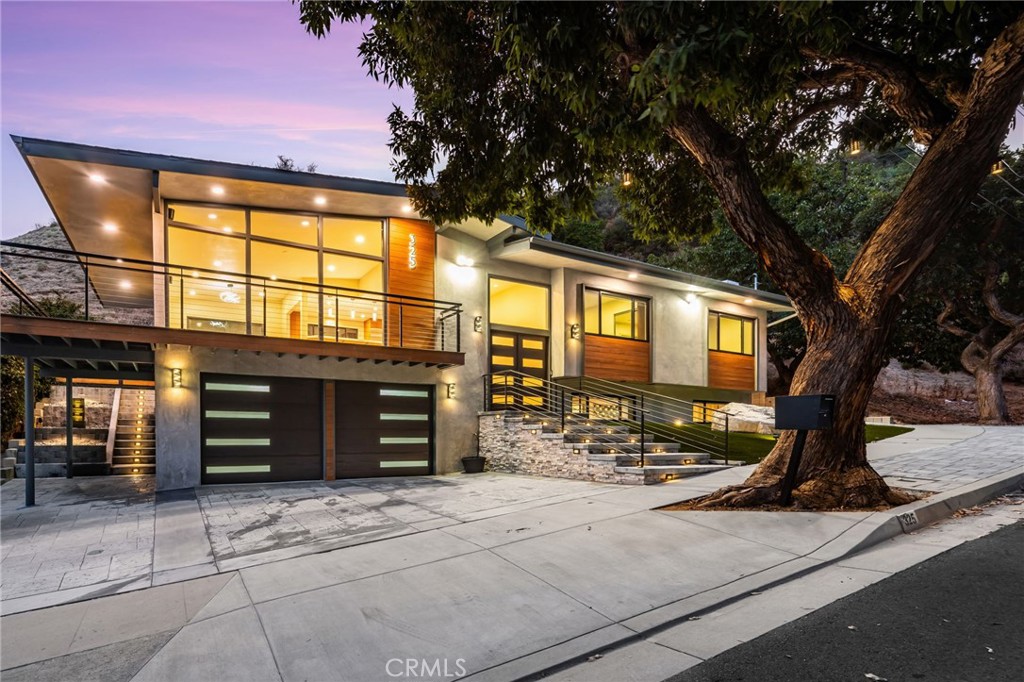 Perched against the serene backdrop of the San Gabriel Mountains, this completely reimagined Monrovia residence is the epitome of luxury, design, and craftsmanship. With sweeping views of the city and the occasional deer strolling by, the setting is as breathtaking as the home itself. Every inch has been meticulously remodeled with top-of-the-line finishes, designer lighting, and cutting-edge technology—creating a true showcase of modern elegance.
Step inside through a dramatic double-door entry that sets the tone for the sophistication and style found throughout the home. The main level features 3 spacious bedrooms and 2 spa-inspired bathrooms, each appointed with custom white oak cabinetry, porcelain tile, and high-end fixtures that strike the perfect balance of warmth and refinement.
The living room is a showstopper, showcasing floor-to-ceiling windows, a wraparound balcony with panoramic views, and a built-in 75-inch TV for an immersive entertainment experience. Sophisticated lighting lets you set the perfect mood with customizable brightness and color, while backlit TVs and ambient night lighting add to the home’s sleek, modern ambiance.
The chef’s kitchen is both functional and beautiful, boasting custom bamboo cabinetry, quartz countertops, brand-new Thermador stainless steel appliances, and under-cabinet lighting that enhances every thoughtful detail.
Downstairs, the expansive lower level is built for entertaining and flexible living. It features a spacious lounge area with a built-in bar, an additional room, a full bathroom, and an oversized laundry and storage space equipped with a sleek flat black LG washer and dryer.
Tech-savvy throughout, the home is wired for Sonos surround sound and includes a Google Nest system for smart climate control and home automation. The two-car garage is finished with durable epoxy floors, completing this modern masterpiece.
This extraordinary home blends high design, modern convenience, and natural beauty in one of Monrovia’s most scenic and sought-after locations. A truly rare and remarkable find.