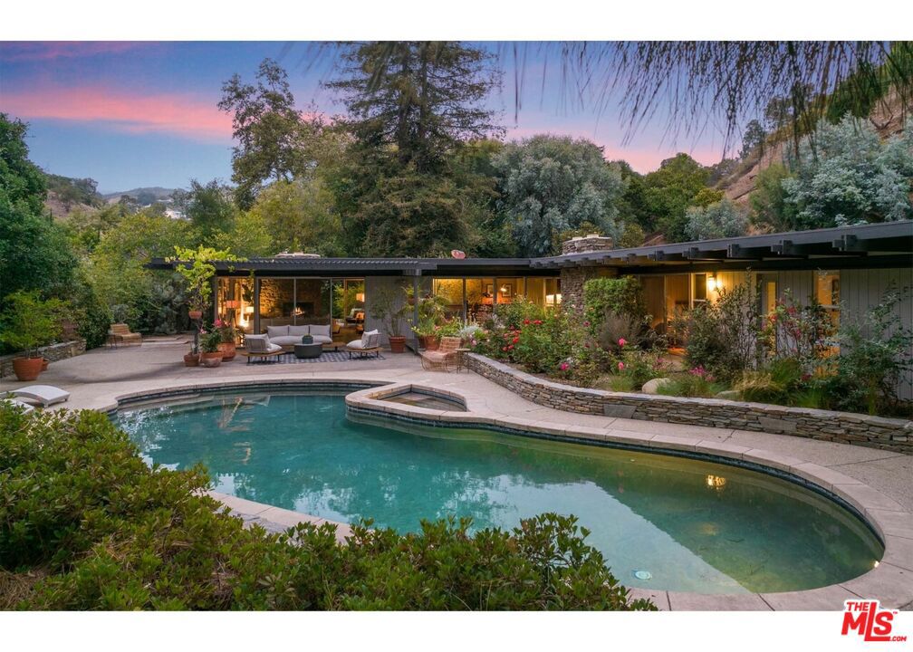 Never before on the market. This extraordinary example of mid-century modern architecture awaits the discerning buyer. The property comprises ~1.4A up a secluded driveway on a private road in prime Pacific Palisades. From 1958-1960, renowned architects Karl Klokke and Paul Wuesthoff designed and built this home as an avant-garde residence for a prominent local family. Sited on the lot to capture the beauty of the gardens and majestic trees, every room opens to a beautiful green private oasis. Floor to ceiling windows, sliding glass doors, post and beam design, flat roof and large overhangs define this one story masterpiece of indoor outdoor California living. Serenely private, the outside sitting and dining areas surround the magical pool, spa and rose garden. From the front door, a long gallery hall leads to a sunken living room with a cement floor, stone fireplace and walls of glass, continuing to the simple yet elegant dining room, with built-in cabinets and a modernist bar. The open plan kitchen seamlessly shares space with the family room with half walls and brick fireplace. Two separate bedroom wings allow simple functionality; three bedrooms on one side of the house and the primary suite on the other. The primary suite has a large bedroom, separate office, a zen meditation and massage room, two baths and a small kitchen. A bonus exterior studio/workout room is adjacent to the carport, the fruit orchard and orchid house. Original plans available. Trust sale. See Agent Remarks. First time offers will be reviewed is on August 2nd. No open houses, all showings by appointment only.
