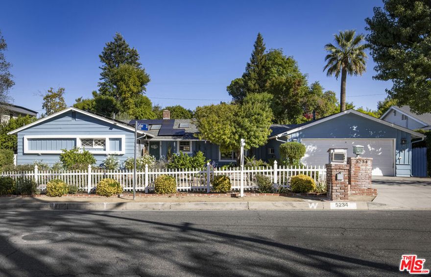 Nestled in the heart of Tarzana, just south of Ventura Blvd, this 5-bedroom, 4-bathroom Ranch-style pool home is a rare gem - lovingly maintained by the same family for nearly 40 years. Tucked behind a white picket fence, it offers the perfect blend of open-concept living, comfort, and incredible indoor-outdoor entertaining. Step inside this 1956 beauty and discover a cozy living room with beamed ceilings, a brick fireplace, and rich hardwood floors throughout. The oversized formal dining room, bathed in natural light from multiple exposures, easily accommodates dinner parties of eight guests or more, with views of the lush, park-like backyard and pool. The heart of the home is a gourmet eat-in kitchen featuring granite countertops, high-end appliances, and custom cabinetry with abundant storage. Just off the kitchen, a spacious family room with pitched, beamed ceilings is flanked by glass sliding doors on both sides, creating seamless flow to the expansive outdoor living areas. Positioned behind the family room is a versatile guest suite with its own full bathroom- ideal for multigenerational living - along with a dedicated laundry room with side-by-side washer and dryer, and direct access to the two-car garage. On the opposite side of the home, the primary suite offers a peaceful retreat with a large walk-in closet and a spa-like en suite bathroom featuring a soaking tub. Two additional generously sized bedrooms share a full Jack-and-Jill bathroom with both a separate shower and tub. A charming fifth bedroom, currently used as an office, plus an additional full bathroom in the hallway, completes this enviable floorplan. Outside, the expansive backyard (nearly 20,000 SF) is a private oasis - fully enclosed by mature trees and hedges. At the far end of the yard, you'll discover an oversized, gated pool and spa with a generous shallow area, perfect for kids to splash and play all summer long. An outdoor kitchen with built-in storage, multiple covered dining and lounging areas, and ample room for a basketball hoop or pickleball court complete this entertainer's dream yard. Additional highlights include new designer lighting, new carpeting in primary closet, fresh interior painting, a two-car garage with an EV charger, fully paid-off solar panels for reduced utility costs, and a location just moments from some of the San Fernando Valley's best restaurants and shops such as Scratch Bar & Kitchen, Taj Mahal, Cici's Cafe, Asal Bakery, The Brothers Sushi, Casalena, Sadaf, Borekas Sephardic Pastries, Anajak Thai Cuisine, and Osteria La Buca. This special enchanting Tarzana retreat offers space, privacy, and style in one of the Valley's most desirable pockets.