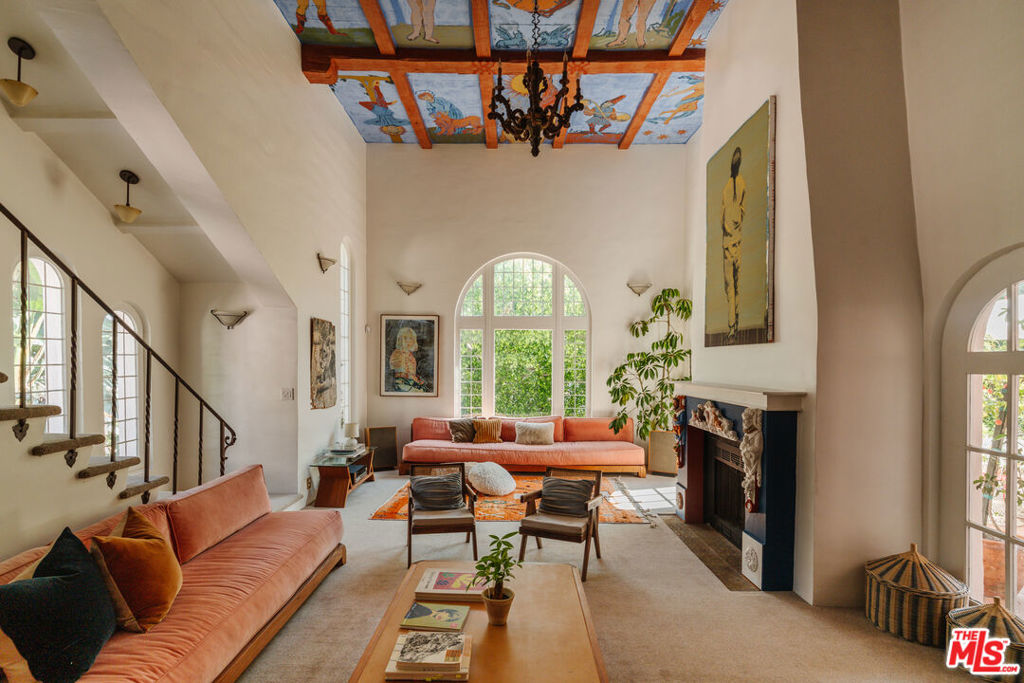 Located in the heart of Los Feliz and adjacent to Laughlin Park, this gated and private 3BR/3BA Spanish home circa 1924 blends original romantic Spanish details with modern updates. Soaring beamed ceilings with iconic hand-painted murals, vibrant colors, and abundant charm are found at every turn. The home offers a flexible downstairs layout with a spacious family room, formal dining room, updated contemporary kitchen and guest bedroom with bath. Upstairs is a balcony library leading to a second bedroom and bathroom, as well as the primary suite with custom millwork wardrobe and gorgeous en-suite bath with steam shower. A series of arched French doors open to a private balcony patio with sweeping views of Downtown Los Angeles and beyond, framed by jasmine and palm trees. A tiled patio and lushly landscaped garden offer a private escape, featuring a petanque court and multiple areas for dining and entertaining. Located just minutes from Griffith Park, Hollywood, and Los Feliz Village, come discover this true work of art in one of the city's most desirable neighborhoods.