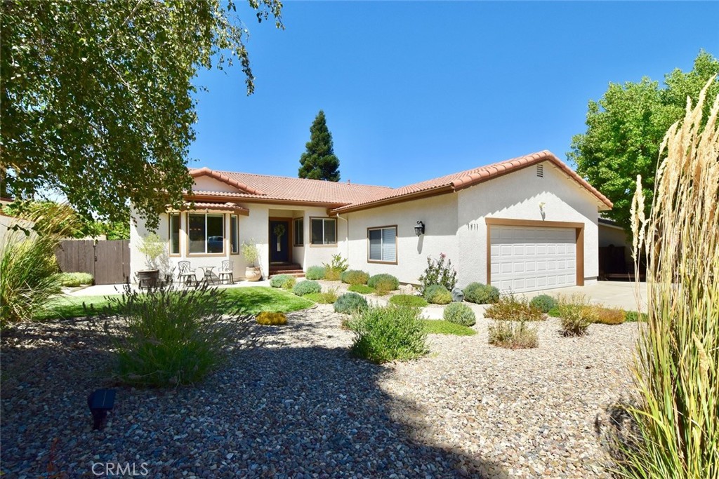 Experience lake living in this elegant home nestled within an upscale Heritage Ranch neighborhood at Lake Nacimiento. This beautifully remodeled single-level residence offers 3 BR, 2 BA, and approx. 2,195± sq. ft. of living space on a ¼+ acre lot. The home has a modern, open floor plan and has been extensively upgraded by the sellers, featuring a gourmet kitchen with Omega maple cabinetry, quartz counters, pantry, wine rack, soft-close drawers, roll-outs, and Thermador commercial-grade appliances with a dual-fuel range. A bright breakfast nook opens to the expansive Trex deck—perfect for indoor-outdoor living—and offers cabinetry for storage, serving, or coffee station. The layout includes formal living and dining rooms with sculptured ceilings and a bay window overlooking the front yard and nearby oak-covered hills, plus a spacious family room with new pellet stove and glass door to the back deck. Throughout the home you’ll find attractive and durable European oak engineered wood flooring, new dual-pane UV windows with wood shutters, fresh interior paint, recessed and pendant lighting, new ceiling fans, plus upgraded attic insulation. Together these improvements enhance comfort, energy efficiency, and long-term value with stylish attention to detail. The primary suite offers deck access—perfect for quiet early mornings—a walk-in closet with custom maple organizer, and a remodeled bath with quartz counters, dual vanities, soaking tub, and large shower. Thoughtful design places the suite slightly apart from the guest bedrooms, providing added privacy for a true retreat. Two guest bedrooms, a full bath with double sinks, and hallway storage complete the interior. Outdoor living is exceptional, featuring a landscaped backyard oasis with stamped concrete, flagstone pathways, built-in firepit (wood burning w/ propane option), dry-stacked stone wall, drip irrigation, and lawn with colorful plantings. Relax under an umbrella, enjoy the fountain, or take in peaceful views of the greenbelt and hillsides, all framed by mature shade trees and newly replaced fencing/gates. The oversized garage provides workshop space, overhead storage, upper cabinets above the garage door, and laundry with washer/dryer. An 11’ wide by 55’ deep gated concrete pad provides space for multiple vehicles, boat, or RV. Heritage Ranch residents enjoy access to Lake Nacimiento, pools, sport courts, parks, trails, equestrian facilities, dog park, grocery store, restaurant, school, and more.