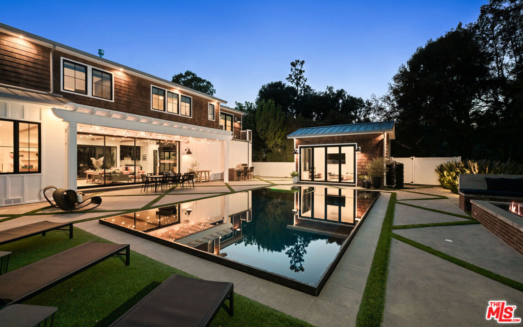 Welcome to this stunning modern-traditional home ideally situated on a quiet cul-de-sac in the highly sought-after enclave of Royal Oaks, Encino. Built in 2018, this newer construction (not a remodel) offers a limited builder warranty and is designed for the discerning buyer who values both elegance and modern conveniences. With impeccable curb appeal, the gated property immediately captures attention, inviting guests into a soaring foyer with high ceilings and European oak floors throughout. The elegant living room features a grand fireplace, seamlessly flowing into a formal dining room perfect for hosting. A glass-enclosed private office with custom built-ins provides a refined workspace with exquisite finishes. The heart of the home is the chef's gourmet kitchen, a true masterpiece. It boasts double islands with Calcutta quartz counters, a 60-inch Wolf range, a 72-inch built-in Sub-Zero fridge, a large walk-in pantry, and a butler's pantry. The spacious breakfast area is adjacent to a cozy family room, which showcases beautiful built-ins and a fireplace. Floor-to-ceiling pocket glass doors open to a sprawling entertainer's yard, creating a perfect indoor-outdoor flow. The main floor also offers a state-of-the-art home theater, a stunning powder room, a mudroom, and a wrought-iron, glass-enclosed wine cellar.Upstairs, the romantic master suite is a true retreat, featuring a sitting area and a dual-sided fireplace. The two expansive walk-in closets and a spa-like master bath complete with a soaking tub, glass rain shower, dual sinks, makeup vanity, and two water closets offer ultimate comfort and luxury. The entertainer's yard is a spectacular oasis with a zero-edge sparkling pool and spa, a fire pit, a built-in barbecue, and a pool house with its own bathroom. Thoughtfully designed for modern living, this home includes a full metal roof throughout, all underground utilities, a whole-house water filtration system, and smart home technology with integrated Control4. Additional features include a three-car garage and the option to purchase the home partially furnished. This exceptional residence offers a luxurious lifestyle just moments away from Encino's finest shops, dining, and more.