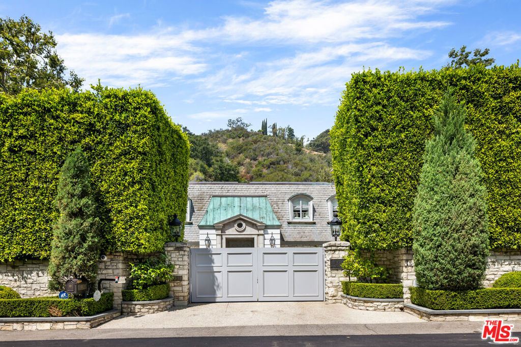 The style and sophistication of Fifth Avenue just two houses from the Hotel Bel-Air. Featuring renovations by renowned architect John Elgin Woolf, the impeccably pedigreed Hollywood Regency-style home neatly encapsulates the best of Woolf's work--a dramatic oversized entry, black lacquered double front doors, oval shaped windows, and gracious symmetry--all beneath a mansard roof. The exceptionally private home is well-suited for effortless indoor/outdoor entertaining on a grand or intimate scale--the French doors of the large formal dining room and a bright living room, with fireplace, both open to the expansive covered terrace with outdoor fireplace, in-ceiling heaters and multiple seating areas. Conveniently located on the first floor, the primary suite overlooks the private hedged garden and features a fireplace with marble surround and two full bathrooms with walk-in closets. The Chef's kitchen includes banquette seating for casual in-kitchen dining. A library and bar off of the living room are perfect for a night cap and movie. Upstairs is another large sitting room and four generously sized secondary bedrooms. The guest house has a bedroom and bath with a private entry, and a separate gym, office and full bath. Set on one acre in lower Bel Air, the manicured grounds include a grassy lawn, large pool and spa, vegetable garden, and a hidden, turfed play area that leads to a quiet knoll under a grove of heritage Oaks. Available for the first time in two decades, this is a rare opportunity to own a well-appointed estate of contemporary elegance and architectural significance in Los Angeles' most exclusive neighborhood.