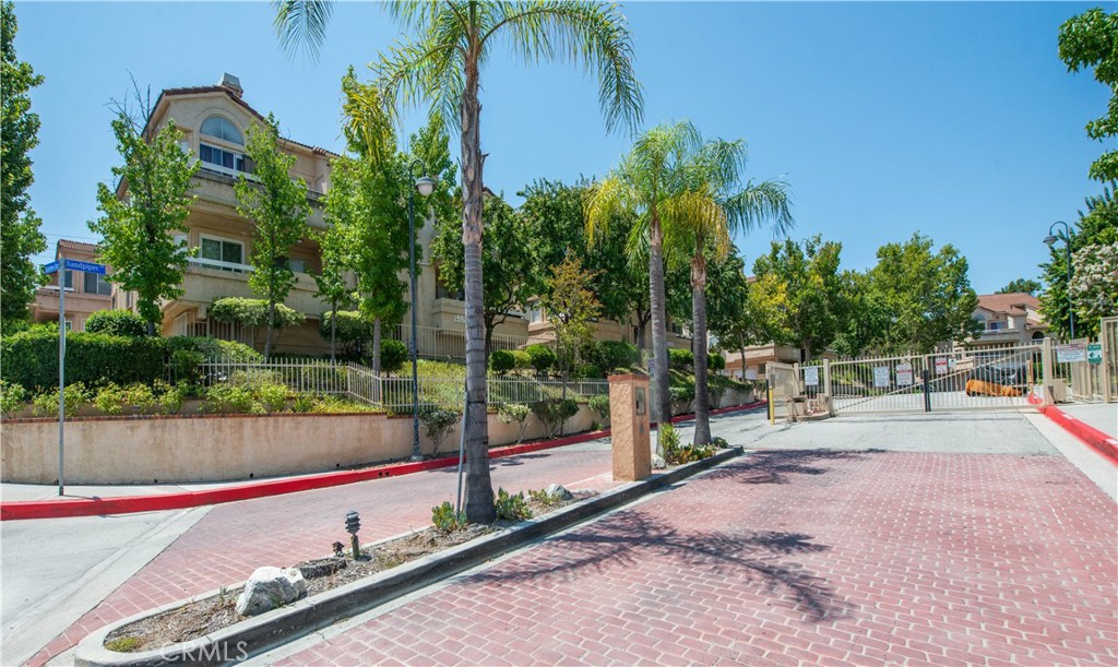 Located in a beautiful pocket of Newhall, this gated, top floor corner condo offers a peaceful retreat in a serene neighborhood. The spacious 3 bedroom, 2 bath layout is move-in ready! Highlights include a modern kitchen with quartz countertops, a cozy fireplace in the living room, sweeping views of the hills and mountains, and a private en suite primary bedroom. A versatile loft easily accessible by staircase which features a wet bar. Enjoy the convenience of in unit laundry, generous storage throughout, and a refreshing cross breeze. The well maintained community pool is just steps away, and the neighborhood is perfect for scenic walks and easy living.