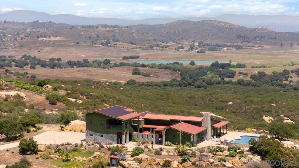 West End of Ramona, this is a Hubbell and Hubbell ICF design made for comfort, sustainability, energy efficiency and fire resistance. Seller owned solar electric and solar water systems. Breathtaking panoramic views abound.Has 8.47 acres with 1575 SF workshop and 609 SF Casita above the spacious 4 car garage. Fronts the 3500 acre Ramona Grasslands. Located on a private road with vineyards and avocado orchards. Multiple ingress and egress options for quick/easy access to amenities and main roads.Ramona airport is in viewing distance. Horses & vineyards permitted.See Documents and Virtual Tour for more information. The main house is 2895 SF with a 609 SF Casita built above the 4 car garage & 1575 SF steel workshop that is an aircraft hangar. House is constructed with Insulated Concrete Form Technology for sustainability and energy efficiency. Natural lighting,energy efficient appliances & plumbing fixtures,owner owned solar water heating and solar electric production plus 2 Tesla batteries add to energy savings.Low water landscaping close to the house.Built to highest US Green Building LEED standards but not certified. City water. House is dual plumbed for waste water release into the septic system and gray water usage in the yard. 2 new complete mini split systems added last month. The best part of the property are the VIEWS! Mt Woodson, Julian, Mt Palomar Observatory, Ramona Airport, Ramona Grasslands and abundant native wildlife all seen from inside the house plus the pool and barbecue areas. Steel and fiberglass water tanks DO NOT Convey.