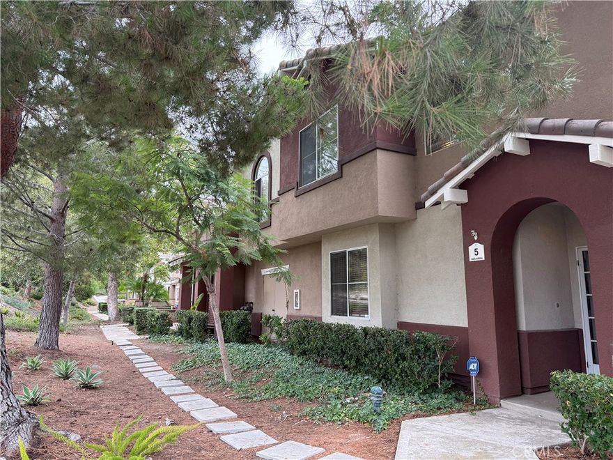 Occupying a nice corner in a serene tree-line setting of the Vineyards community, this beautiful townhome offers both the luxurious living and views of the nature. 3 bedrooms, 2.5 baths, 2 car garage with a direct access to the unit. Bright and inviting, the living room boasts high ceilings, a fireplace, and a glass slider to patio. The upgraded kitchen includes granite countertops, antique white cabinetry, all stainless steel appliances, bar sitting, and a lovely built-in bench below the kitchen window. Well appointed master suite with high ceiling, a walk-in closet, ensuite bath with dual sinks, newer shower doors, and skylight. Beautiful ceiling fan on the hall upstairs, controlled by a remote. One secondary bedroom has mirror closet and the other one has a cute built-in bookshelves by the closet. Individual laundry room with storage cabinets. Newer water heater. Newer paint in the living room, dining room, powder room, and the master bath/walk-in closet. Newer flooring, including the beautiful luxury planks in both master bath and hall bath and entire downstairs. Whole house re-piping done in 2022. A fully fenced patio--plenty of room for your patio furniture and flower pots!  Beautiful views from every room of the home!  Steps to the tot playground and gazebo.  Enjoy the HOA pool, spa, and picnic areas. Award winning schools. Within walking distance to shops, dining, and movie theaters. Short distance to parks and Whiting Ranch Wilderness Park for hiking and mountain biking. Close to the 241 toll road. Short drive to the Irvine Spectrum. Small pets are considered! A must see! Don't miss out!