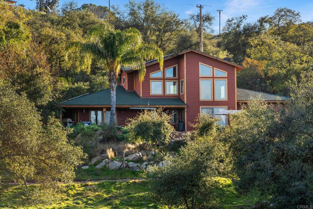 Nestled in the peaceful hills of Alpine, the stunning 20-acre Ranch offers a rare blend of seclusion, luxury, and natural beauty. This exceptional property features a thoughtfully designed custom home, expansive equestrian facilities, a private pond, and a resort-like pool and jacuzzi area, all framed by breathtaking views of the Cuyamaca Peaks and Viejas Mountains. Bordering the untouched Cleveland National Forest, it truly embodies the essence of country living with complete privacy and tranquility. The 3-bedroom, 2-bathroom home is a masterpiece of craftsmanship, showcasing solid oak flooring, imported travertine tiles, and custom wood details throughout. High ceilings with exposed wooden beams create a spacious, inviting atmosphere, while the open ranch-style layout is perfect for both everyday living and entertaining. A versatile loft provides endless possibilities, whether as an additional bedroom or a large office.The gourmet kitchen is a chef’s dream, featuring a generous island, ample wood cabinetry, stainless steel appliances, and a walk-in pantry. The large primary bathroom is a retreat in itself, complete with a luxurious jacuzzi tub and tiled shower. Two additional bedrooms each offer sliding doors leading to the outdoors, while the home also includes a guest bathroom and a convenient laundry room. Designed for comfort and efficiency, the home is equipped with fire-resistant Hardie board siding, Anderson wood sash windows, a dual-zone HVAC system, and a whole-house water filtration system. The stunning surroundings can be fully appreciated from the wrap-around front porch, the expansive pool and spa area, and the beautifully landscaped gardens. This rare property offers the ultimate in peaceful, private country living, just waiting to be called home.