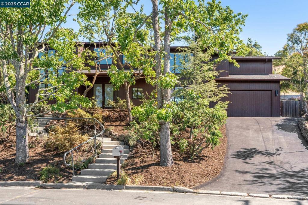 This stunning 6-bedroom, 4.5-bathroom residence is designed for both grand entertaining and everyday comfort. A dramatic curved staircase with sleek glass balustrades welcomes you into the heart of the home, where vaulted ceilings and floor-to-ceiling windows flood the space with natural light. The chef’s kitchen is equipped with stone countertops, high-end appliances, a walk-in pantry, an additional pantry closet, and a built-in wine rack—perfect for hosting or for quiet evenings in. A downstairs bedroom with its own en-suite is perfect for guests or for multigenerational living, while a convenient half bath adds extra flexibility. Upstairs, the primary suite feels like a private retreat, with a walk-in closet featuring custom shelving and drawers, a spa-inspired walk-in shower, and a private balcony overlooking the lush backyard and uninterrupted open space. You'll also find a spacious laundry room, two loft areas, and two additional full bathrooms upstairs, providing plenty of room for everyone. Step outside and enjoy the beautifully mature landscaping, highlighted by elegant Japanese maples, a covered patio, a tranquil koi pond, and a flat grassy lawn—all framed by a serene backdrop of nature.