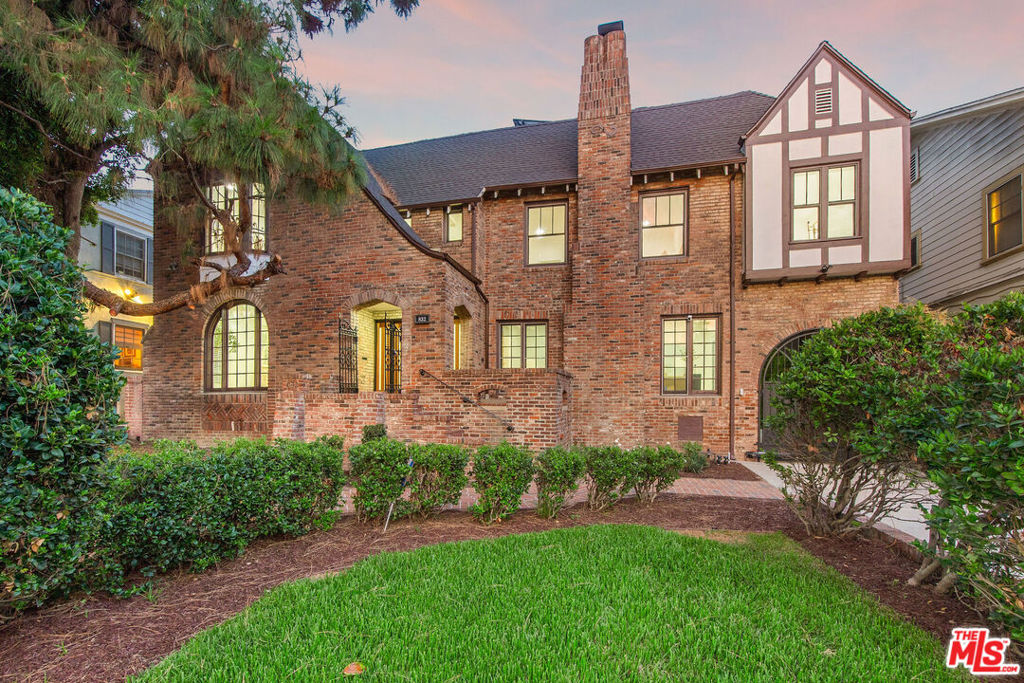 Romantic old-world charm meets modern luxury in this reimagined English Tudor, perfectly situated within Windsor Village HPOZ of Hancock Park. Behind manicured grounds and a majestic pine, the renovated interior unfolds with wide-plank oak floors, airy open-concept living spaces, and a statement staircase framed in black iron. The chef's kitchen features premium stainless steel Thermador appliances, while brand-new Panorama sliding doors connect the indoors to a true entertainers backyard with a covered patio, built-in BBQ, sink, fridge, and storage. Recent updates include new plumbing, electrical, ductwork, dual AC units, roof, paint, and paid for solar panels. The garage is recently finished with new doors, epoxy floors. The spa-inspired primary bath boasts a freestanding tub, porcelain shower with gold trim, and abundant natural light. Additional highlights include a wine cellar, decorative fireplaces, and an option for a sixth bedroom making this historic-meets-modern gem truly turn-key.