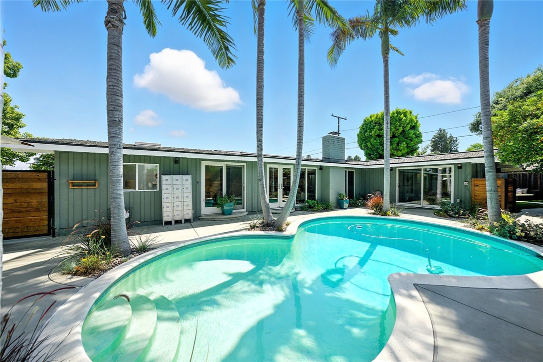 Welcome to 3109 Pattiz Ave, a stunning 3-bedroom, 2-bath Cliff May Rancho nestled in the highly sought-after Rancho Estates of Long Beach. This architectural masterpiece seamlessly blends timeless mid-century design with modern upgrades, offering the perfect balance of style and functionality. The enclosed patio features mature king palms, multiple citrus trees, built-in bench seating with a gas fire pit, an inviting outdoor BBQ area, and a relaxing sauna to create the ultimate outdoor experience. The sparkling solar-heated pool is the heart of this private oasis, making it the perfect place to unwind or host gatherings year-round. Inside, the classic Cliff May aesthetic shines with exposed beam vaulted ceilings and upgraded wood-framed floor-to-ceiling windows that flood the home with natural light. Modern updates enhance the open floor plan, featuring ceramic tile flooring, a beautifully updated kitchen with a large island, and a seamless indoor-outdoor flow. All three bedrooms are spacious, but the primary suite is its own private retreat within the home. Located on a separate wing, it is a massive space complete with an oversized primary bathroom, which has been thoughtfully designed into a sleek and sophisticated wet bath, adding a touch of contemporary luxury. This serene, private property is located in a quiet interior location on one of the most desirable streets in the Rancho Estates tract. Conveniently located near Cal State Long Beach and next to El Dorado Regional Park, offering amenities such as lakes, bicycle and walking trails, an archery range, and the El Dorado Nature Center. Commuting made easy with nearby access to both the 405 and 605 freeways. Belmont Shore and Orange County are just minutes away. Experience the perfect blend of mid-century charm and modern convenience in one of Long Beach’s most desirable neighborhoods.