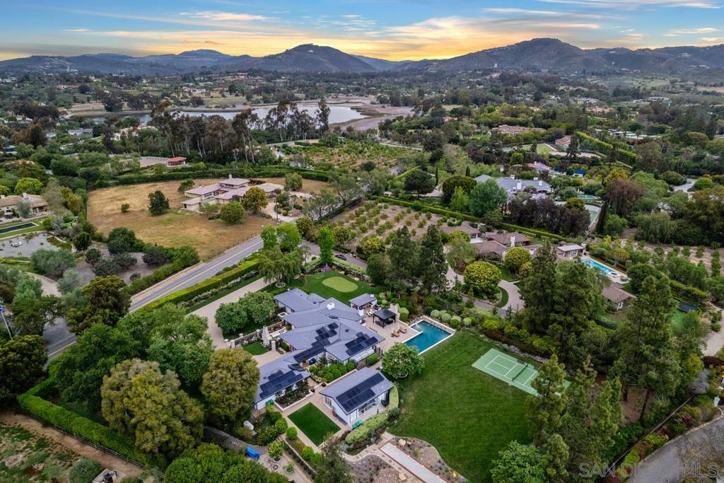 A rare and private 2.24-acre Entertainer’s Dream Estate in the heart of the Rancho Santa Fe Covenant. Located on one of the most cherished streets, this gated single-level compound lives like a private park—lush gardens, citrus orchards, raised stone vegetable beds, and serene water features create a setting that feels worlds away. Thoughtfully designed for seamless indoor/outdoor living, the main residence features 3 bedrooms, 4 fireplaces, a chef’s kitchen with Wood Mode cabinetry, wine dispenser, and adjacent bar lounge. The primary suite includes dual closets and a spa-style bath with freestanding tub. A separate guest house offers full privacy with its own kitchen and living area. Outside, every inch of this resort-style estate is curated for enjoyment—covered outdoor kitchen with Kalamazoo grill, authentic pizza oven, built-in heaters, pickleball court, bocce ball, putting green, and pool/spa with water features. Additional features: SONOS, Lutron lighting, solar with 72 panels, EV charging, backup generator, FLO system, tankless water heater, wine room, and full security system. 3-Car garage, plus plenty of guest parking on property. This is Rancho Santa Fe luxury living at its finest—a lifestyle property built for connection, celebration, and peace.
