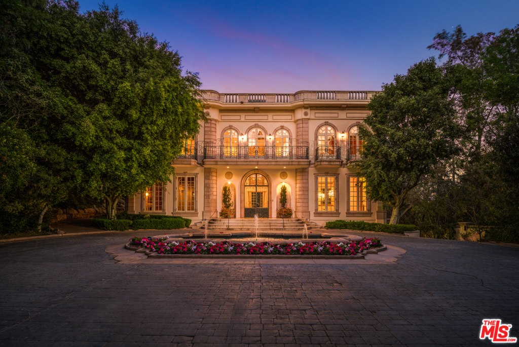 Developed in 1990 by one of the founders of Architectural Digest, rare is the house that dares to emulate a past masterpiece such as Le Petit Trianon, Marie Antoinettes summer palace at Versailles, France and, in so doing, actually exceeds the glory of the original. This magnificent residence situated on an acre of lush matured landscape on Holmby Hills most prestigious street captures the very essence of the 18th-Century French chateau. Beyond the gated main entrance and expansive reflective pool with triple fountains, one enters this classic 11,000 sq.ft residence through 14 foot glass and verdigris wrought iron doors, and is greeted by daylight from a 46 high dome two stories overhead kindling a glow in the marble of the double circular grand stairway. Suspended from the center of the dome is a massive 18th century Baccarat crystal chandelier. Light, refracting from the crystal and gold transports the viewer back to Versailles, and a time of unlimited opulence. Off this majestic space, vast public rooms all with 14 foot high ceilings array themselves in exquisite procession, along with. 80 wide waterfalls, fountains, swimming pool, outdoor fireplace and a N/S tennis court surrounded by the vivid colors of lush gardens and stage.