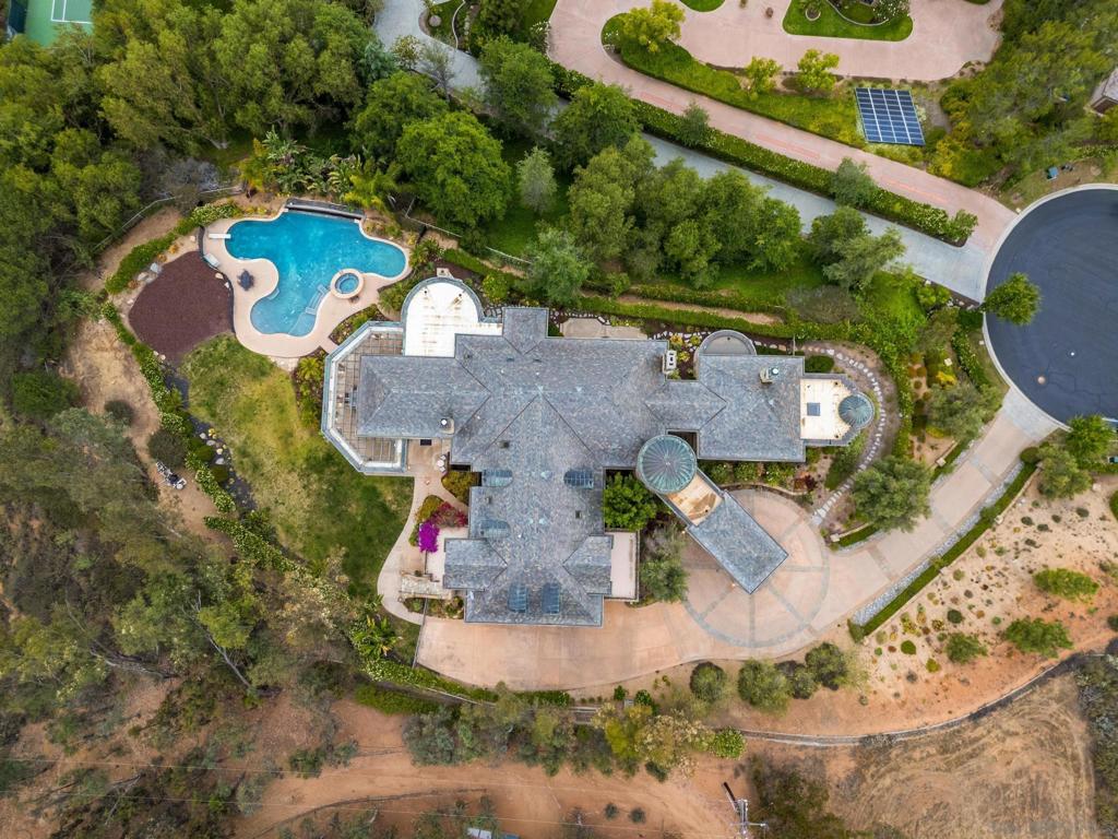 Experience the pinnacle of luxury living at 14380 Ciera Court, a Tuscan masterpiece perched on an elevated cul-de-sac lot in Poway’s prestigious guard-gated community, The Heritage. Crafted with sophistication and designed for both grand entertaining and intimate everyday living, this custom estate spans approximately 11,744 sq ft on a serene lot with panoramic views. The architectural design showcases classic tuscan elements—a stucco exterior, slate-tiled roof, and grand arched entryways—while soaring ceilings and expansive windows flood the interior with natural light. An open-concept layout highlights a chef’s kitchen with oversized island, seamlessly flowing into spacious living and formal dining areas. On the main level, the primary suite serves as a private retreat, featuring a spa-like bathroom and dual walk-in closets. Upstairs, three generous en-suite bedrooms with walk-in closets surround a versatile bonus loft—ideal as a study area, teen lounge, or additional family gathering space. A private attached casita offers the perfect space for guests or multigenerational living. A true rarity in The Heritage, is the expansive finished basement adding a new dimension of living: enjoy your own private movie theater, game lounge, wet bar, and wide-open space perfect for large-scale entertaining. Step into resort-style outdoor living with a vanishing-edge pool, spa, outdoor kitchen, covered loggia with fireplace, and lush landscaping—framed by sweeping views.