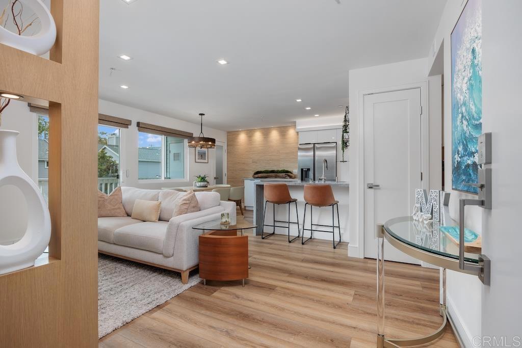 Minutes from downtown Encinitas and Moonlight Beach, this fully renovated condo blends custom builder craftsmanship with high-end finishes. The living area features smooth white walls, Sherwood Oak luxury vinyl plank flooring, and a white oak feature wall with a floating backlit TV mount over textured plaster panels. Milgard sliding door with Somfy motorized shades open to a private west-facing balcony. The kitchen offers striking honed marble countertops with a waterfall-edge and peninsula, premium s/s appliances, custom pantry shelving with opaque glass door, and extended cabinet for extra storage. Two spacious bedrooms include a primary bathroom with a raised-ceiling, custom oak vanity, heated tile floors, bidet, and lighted vanity mirror. Features include: 1-car garage with storage, upgraded electrical subpanel, new Milgard windows, recessed LED lighting with dimmers, raised ceilings in both baths and hallway, high-efficiency AC and furnace, and new solid core Shaker doors along with 5” base and case moldings. Nestled in the well-maintained community of West Hampton Cove with lush landscaping and two spas, this home offers the perfect blend of a relaxing retreat while still being close to everyday conveniences. Just minutes to shops, restaurants, beaches, freeway and top-rated schools: Capri Elementary, Diegueno Middle and La Costa Canyon High School. Buyer and buyer’s agent to verify all in MLS prior to COE.