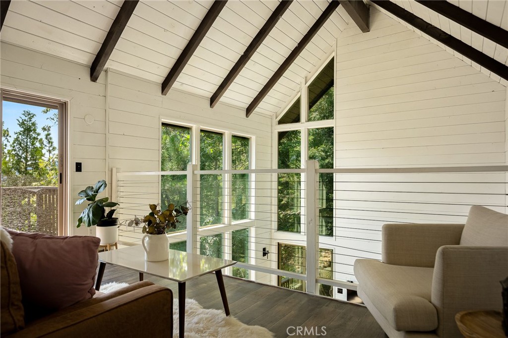 Welcome to Little Bear Lakehouse, featured in the New York Times, this quintessential post–mid-century retreat masterfully blends timeless design with modern updates. Located on a spacious lot hugged by lush pines, this three-story architectural gem captures the spirit of the late 1960s with clean lines, open spaces, and a seamless connection to nature. This striking property features crisp shiplap accents and expansive walls of glass paired with a commanding stone fireplace, creating an airy yet inviting scene that honors its mid-century roots. Inside, vaulted ceilings and exposed beams amplify the sense of openness, while elegant floor-to-ceiling glass floods the interior with natural light and frames tranquil forest views. The striking stone wall anchors the fireplace, a classic mid-century focal point that adds texture and warmth. The fully remodeled kitchen introduces sage green cabinetry and stone accents, thoughtfully combining vintage-inspired colors with contemporary functionality. Downstairs features a romantic primary bedroom, a guest bedroom across the hall, a fully remodeled full bath, and a convenient laundry area, all designed for relaxed mountain living. A guest half bath on the main level enhances everyday convenience and makes visitors feel at home. Upstairs, a bright, open loft and a separate guest bedroom with its own private deck and peekaboo lake view offer perfect spots for quiet mornings or peaceful evenings under the stars. Multiple outdoor decks invite lounging, dining, and entertaining beneath the pines. Fire up the BBQ on the deck and savor meals surrounded by nature on this spacious corner lot that offers ample space to roam and unwind. A pull-through horseshoe driveway accommodates parking for an RV and a boat, perfect for those who embrace the lake lifestyle. As a bonus, Lake rights provide access to all the recreational amenities Lake Arrowhead is known and loved for.