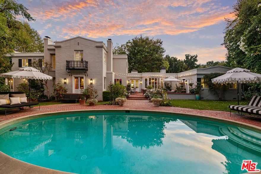 Located on lower Benedict Canyon Drive in Beverly Hills Proper is this two-story, five-bedroom, six-bath residence, artfully designed and built in 1929 with later remodeling done by esteemed architect John Elgin Woolf. One of the few remaining Beverly Hills homes featuring Woolf's Hollywood Regency stylings: his signature oval windows, large architectural doors, dentil moldings, hardwood flooring and French windows and doors.The house is sited on an expansive, private-feeling, gated, walled, and maturely wooded lot. The floorplan is classic and has easy flow from room-to-room and to the outdoors. The two-story foyer sets a graceful tone with its fireplace, sitting area and sweeping staircase. The formal living room with its tall ceiling, built-in bookcases and stately fireplace opens through French doors to the backyard. The formal dining room is perfect for either a large dinner party or a more intimate gathering.  The kitchen and family room are a chef's and entertainer's dream. This bright, skylit area opens to the backyard and serves as the casual wing of the house. Clad in Carrara marble and outfitted with top-tier appliances, the kitchen features a center island with seating and a multitude of built-ins. There's a bar area, a butler's pantry and temperature-controlled Sub-Zero wine storage. Connecting seamlessly to the kitchen is the family room area with built-in bookcases and a fireplace. It also has a breakfast niche for informal gatherings and every-day dining. A jewel box of a den/study is warmed by yet another fireplace and serves well as a library or home office. Two guest bedrooms, one of which is currently used as a music room, both have an associated bath. A laundry room, a powder bath and convenient direct-access to the garage complete the first level.Upstairs feels expansive with its three sunbathed bedrooms. The primary suite has a lovely sitting area and a luxurious, recently redone primary bath clad in stunning marble. It features a large soaking tub, a separate shower, dual vanities and a Juliet balcony overlooking the grounds. Closet space is plentiful here with both a walk-in closet and a wall of wardrobe spaces. The two additional bedrooms are large and ensuite. An additional flexible space can serve as a computer station or homework area.The grounds are private and park-like, perfect for entertaining under the Southern California sun and stars. The backyard includes a covered cabana overlooking the oval-shaped pool. There are brick patios for outdoor lounging and dining. There are tranquil grassy expanses ideal for swings and other activities for children.  The driveway offers off-street parking. Beverly Hills Police, Fire and Beverly Hills Schools. Moments to Rodeo Drive and to all the shopping and dining Beverly Hills has to offer. Near to Century City, to Westwood and to UCLA.