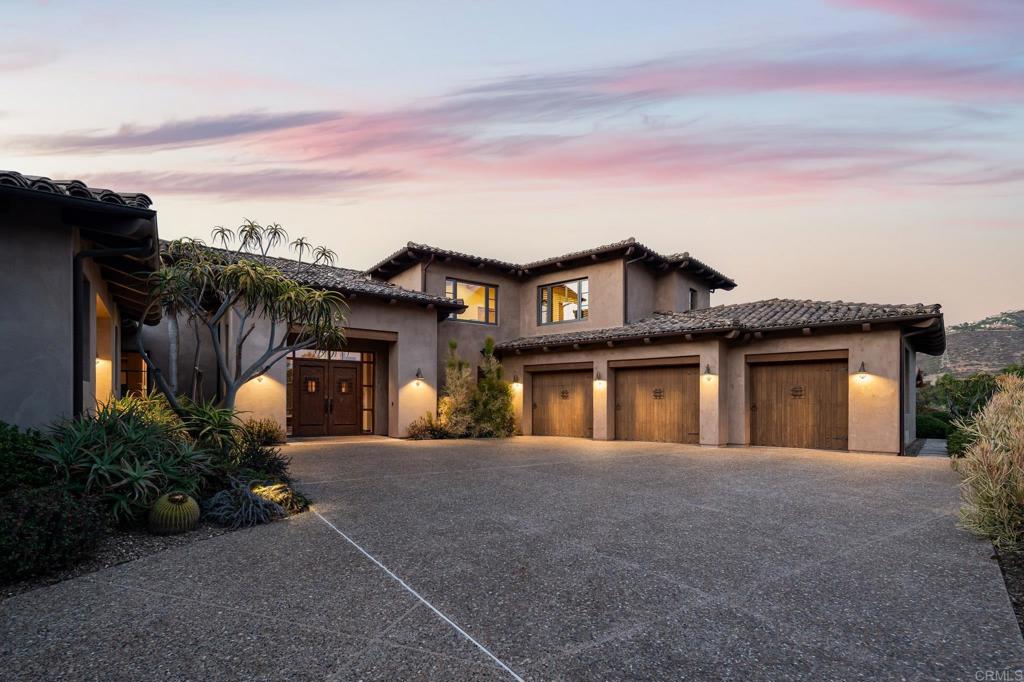 Tucked inside the prestigious enclave of The Bridges of Rancho Santa Fe, this 4,985 sq. ft. residence blends timeless elegance with warm Southwestern-inspired design elements. Set on a half-acre, the home welcomes you with earth-toned stucco walls, rustic wood accents that echo the spirit of the desert Southwest. Inside, the open floor plan is elevated by rich hardwood flooring, hand-hewn wood beams, and textured plaster walls that create a rich, organic ambiance. Niches and curved passageways add architectural interest, while wrought-iron light fixtures cast a soft, inviting glow. The kitchen embodies Southwestern craftsmanship, with warm alder cabinetry, clean modern backsplash, and natural stone counters. A warm stone fireplace anchors the living room, providing cozy charm alongside expansive windows that frame garden and golf course views. The primary suite is a private retreat, enhanced with Terracotta-inspired tones, a beamed ceiling, and spa-like bath. Outdoor living is seamlessly integrated, with a covered loggia, tiled patio, and desert-inspired landscaping that pairs native succulents with lush Mediterranean plantings. Completing the picture is a perfect setting for relaxation or entertaining under Rancho Santa Fe’s starlit skies