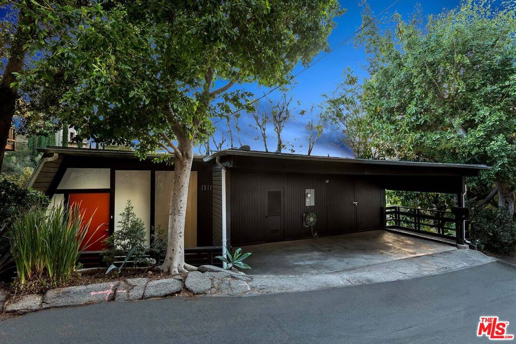 This reimagined residence has been given a stunning designer renovation while preserving the essence of iconic modernists like Richard Neutra, Harry Gesner, and the Case Study homes. A dramatic frosted-glass entry leads into a spacious open-concept living area. The angled living room wall is wrapped in tongue-and-groove planks that rise into soaring ceilings, setting the stage for both warmth and drama. Post-and-beam details and walls of glass stretch the length of the south-facing home, opening every room to a generous deck with sweeping views of Laurel Canyon. Light floods in throughout the day, and from your perch in the trees you can watch deer, coyote, and other wildlife pass by; all while being just minutes from the Sunset Strip, Studio City, and the major studios. The renovation includes updated flooring, new front and rear decks, Nest-controlled HVAC, upgraded electrical and plumbing, lighting, tankless water heater, and Milgard sliding glass doors. The chef's European-inspired kitchen and skylit bath feature custom cabinetry, quartz counters, Carrara marble mosaic tile, and designer fixtures, paired with top-tier stainless steel LG appliances including a gas range, vented microwave, dishwasher, refrigerator, washer, and dryer. The freestanding wood-burning fireplace is accented with glass tile, while original cone light fixtures and louvered windows highlight the authentic midcentury character. With its blend of architectural pedigree, thoughtful modern upgrades, and an unbeatable setting, this Hollywood Hills treehouse is a rare opportunity for a buyer with an eye for design. Weekly gardener included.