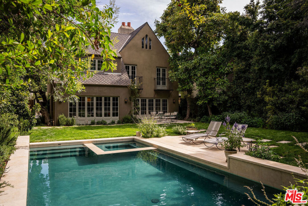 Set behind the private gates of Laughlin Park, one of Los Feliz's most coveted enclaves, this elegantly reimagined residence offers a timeless blend of artful craftsmanship and thoughtful design. Spanning over 4,600 square feet across a main house and guest house, the property has a supremely livable layout where each space flows effortlessly into the next. The interiors are rich and enveloping and include natural stone floors, expansive doors and windows, and curated finishes that creating a feeling of understated luxury. The home is bathed in natural light throughout the expansive yet inviting living spaces. The chef's kitchen features custom cabinetry, marble countertops, and chef-grade appliances that great a blend of style and function. Upstairs, the formal living room boasts a vaulted beamed ceiling that is anchored by a stately fireplace and sets the tone for elegant entertaining. The two-story primary suite serves as a private retreatserene, spacious, and refinedwith a large walk-in closet and dedicated dressing area along with an expansive bathroom with vaulted ceilings. The design beautifully marries the home's original character with modern comfort. The outside areas are a private sanctuary with high hedges and layered landscaping that creates a tranquil backdrop for the glistening pool, while creating a seamless connection to the spacious one-bedroom guest house. Just moments from Griffith Park and the vibrant eateries and shops of Los Feliz, this gem offers a rare combination of sophistication, privacy, and authenticity in one of L.A.'s most desirable gated neighborhoods.