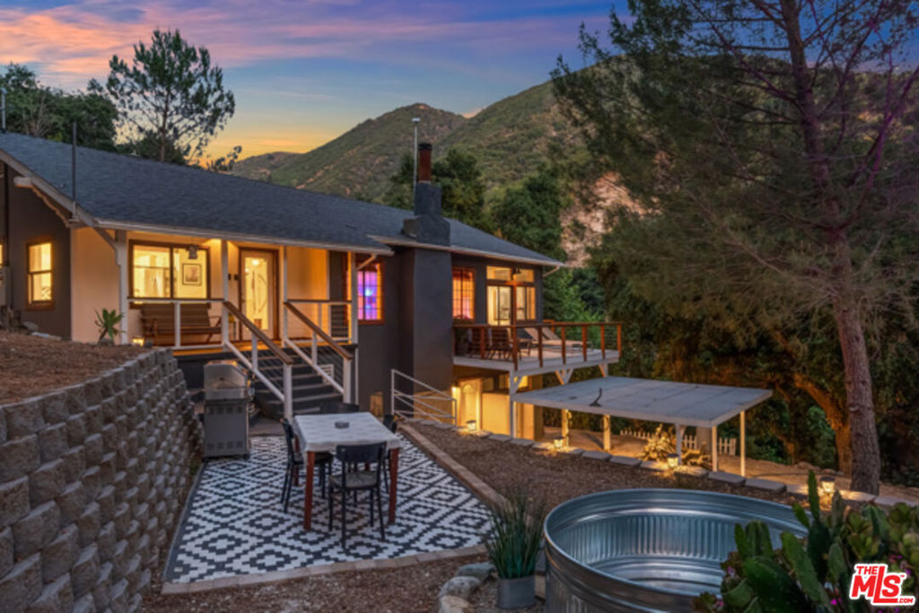 Perched atop the San Gabriel Mountains is this rare private creekside sanctuary surrounded by beautiful oak/pine trees, 360 mountain views and thousands of acres of private national forest land LCA22 zoned 27,708 sq.ft. lot. Feel a world away while being less than 15 minutes to either the LA Valley or Santa Clarita! The upper main house with a modern open floor plan, bright living area, floor to ceiling windowed sunroom/office, vaulted living room and tall ceilings throughout boasts a romantic fireplace and plenty of room to entertain family and friends while taking in the views. With the best in functionality and beauty combined, the sleek meticulously remodeled gourmet kitchen features walnut butcher block countertops, custom backsplash, farmhouse sink, designer brass fixtures and stainless steel appliances. The chic main bathroom has designer tile and custom cedar plank ceiling. The primary bedroom has a large walk-in closet with built-in storage and welcomes plentiful light from the sliding glass door that leads to a new private deck. The upper guest room offers a tall ceiling and its own remodeled half bath. The sunroom/office with a large attached laundry/utility room offers a flexible space that can be used as an office, workout space, den or even turned into another primary bedroom. The roomy downstairs guest house (which is attached) features an open floor plan with a kitchen and oversized full bathroom, complete with its own laundry room and tree-lined views through the wall of glass that opens to a patio next to the creek. It has a private exterior entry door and can also be accessed from a hatch upstairs, giving the option to keep it separate from the main house or connect the two for more main living space. Additional features include new floors throughout, fresh paint, newer water heater, updated electrical/plumbing, mini-split AC/heaters in living room, bedrooms and guest house, and new ceiling fans/lighting fixtures throughout. Enjoy outdoor living on one of several decks and porches or take a dip in the new cowboy pool! The property was recently terraced with multiple levels of block retaining walls, providing plenty of space for vegetable gardens and additional landscaping. There's also a huge level upper graveled area with storage shed, chicken/goat pen and water storage tank that can be used as additional parking or built upon for additional living space/ADU, barn, horse stables etc. The spectacular unobstructed views of the San Gabriel mountains and gorgeous topography are unparalleled within Los Angeles. With plenty of space to entertain and for kids/adults to play, this one-of-a-kind property is an outdoor lover's dream!