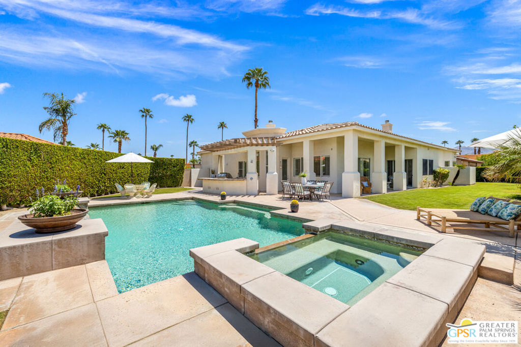 Palm Court at Rancho Mirage! Private grounds, great design, and a backyard oasis that makes the most of desert living. The Tamarisk Country Club neighborhood is the backdrop. Walled, hedged, and framed by palms, the home sits on a quiet cul-de-sac. Inside, tall ceilings and windows fill the home with natural light. The formal living room is anchored by a travertine fireplace, while the chef's kitchen features Wolf double ovens, a five-burner gas cooktop, Sub-Zero refrigerator, and ice maker. The kitchen flows into a breakfast area and a sunny family room with wet bar and wine fridge, creating an inviting space for gatherings. A separate office with its own bath, easily converted into a fourth bedroom, opens to a shaded loggia. The Primary Retreat offers a private escape with a fireplace framed in floor-to-ceiling shelving, and a spa-inspired travertine bath with dual vanities, jetted tub, and oversized shower. Two additional ensuite bedrooms provide comfort and privacy for guests. The backyard is the showpiece of the property. A sparkling saline pebble tec pool with two waterfalls, spa, and sunken sitting areas anchors the outdoor living experience. Manicured landscaping and mountain views enhance the setting, while expansive loggias and a custom outdoor kitchen with Lynx grill and burners create the perfect space for entertaining day or night. Practical touches include a full laundry room, an oversized two-car garage, and dedicated golf cart parking. With its resort-quality backyard and classic design, this Palm Court residence is move-in ready with room for your personal updates. Take the Matterport Virtual Tour for a better sense of flow.