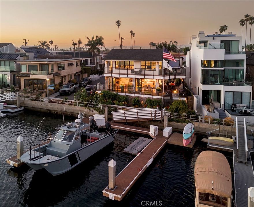 Set along the south-westerly crest of Naples Island, this oversized corner lot consisting of two parcels is an exceptional waterfront residence graced with some of the most captivating views in the region with 90’ of uninterrupted bay. Light, airy, and refined, the property was recently reimagined (2021) – creating a harmonious connection to the outdoor environment. Every consideration was made when enhancing this structure, using quality craftsmanship with an assemblage of natural and engineered materials - optimal for waterfront living. The elegant yet comfortable interior consists of four bedrooms, three baths, and multiple areas for living, dining, entertaining, and relaxation. It reflects a cultivated collection of stylish finishes and conveniences. The home features waterfront walls of glass and abundant windows, complemented by custom millwork and finish carpentry. It includes upgraded tile and brick detailing, along with designer lighting that showcases high-end fixtures and fittings. The kitchen is equipped with Wolf and Sub-Zero appliances, and the home also boasts a mudroom, laundry room, and walk-in pantry. A temperature-controlled walk-in wine gallery with a capacity for up to 400 bottles adds a touch of luxury. The primary suite offers a private retreat with a wrap-around water-view terrace, complete with a sun deck and spa. The private outdoor spaces created with equal endowment offer both a secluded respite and an immersive experience with the charming sights and sounds of the bay. Designed with two levels of waterside terraces and two generous side verandas – engineered to harbor an enclosed annexation of the home if desired – provide a stunning perspective of the sparkling panorama. A rare backyard and an award-winning raised garden complement the lifestyle afforded by this extraordinary presentation. Further distinguishing the property – a professional-grade woodshop and garage with 12-foot ceilings (in-garage parking for two cars with an additional two outside spots) and a new double dock – capable of berthing four large craft (up to 47’) including a catamaran, which are equipped with 20/30/50 amp service. A truly remarkable offering in one of Southern California’s most iconic enclaves.