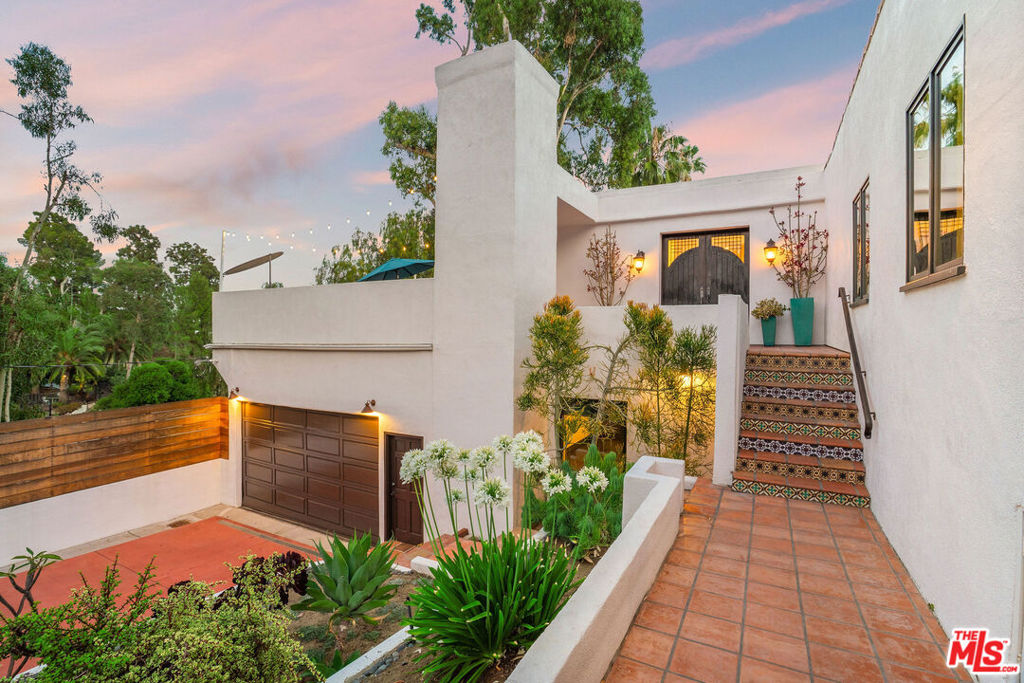 Incredible Mediterranean in Beachwood Canyon, meticulously restored, creating a perfect combination of modern amenities and old world charm. Gated and secluded, a beautifully landscaped walkway guides you to the entrance, where you're greeted by a bright, open floorplan. Spacious family room with gorgeous exposed wood beams and fireplace opens seamlessly to incredible chef's kitchen with large center island, double GE Profile, WiFi- connected ovens, custom abundant cabinets and stone countertops. The entire space opens to an expansive patio, one of several on the property, accessible by Pella sliding glass doors with sliding screens, ideal for dining under the stars with views of downtown. First floor includes two en-suite bedrooms, including a luxurious primary suite that has its own private patio. Downstairs is highlighted by a second primary suite, and also features ample storage, a large bonus room/studio space and laundry room. Impeccably maintained, this timeless beauty offers more storage and privacy than you'd expect, plus tons of driveway parking with a gated drive and 2-car garage with EV charger. Located in lower Beachwood with easy access to great restaurants and cafes.