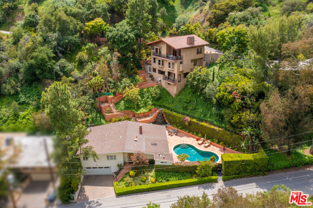 Incredible opportunity for two homes on one large lot in a great Beverly Hills Post Office location near homes listed for almost 50M. Offering endless possibilities, including multi-generational living, live in one & work in the other, or generate income by renting one home out while living in the other, potential for recording studio, guest home, gym and more. The primary home is a mid-century gem with a sundrenched pool and wrap around patio with peaceful fountain. The interior offers much potential with a pitched roof, two ensuite bedrooms each with walk-in closets, a total of 3 bathrooms, a dining area, dual-sided fireplace and kitchen with center island bar. Two car garage and driveway parking. The second home can be accessed by either walking up stairs from the rear yard of the primary residence or via its own front door directly from the street. Equipped with additional space for off-street parking, this second residence offers city and greenery views, a full kitchen, dining room, gym, hot tub, 3 bedrooms (one on each floor), and 3.5 baths. This truly unique offering is loaded with potential and possibilities. Highly coveted Warner School District 10 out of 10.