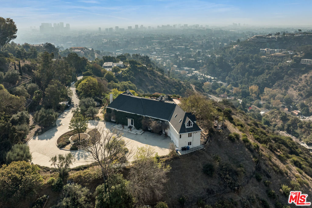 Perched atop a private 8.3-acre promontory in Beverly Hills, this extraordinary tennis court estate offers breathtaking panoramic views stretching from the city skyline to the ocean. A rare combination of seclusion and proximity to the heart of Los Angeles, this residence is a true sanctuary in the hills. Set on an expansive lot, the property boasts a beautifully designed main residence with classic architecture, a grand entry foyer with dual sweeping staircases, and sophisticated interiors bathed in natural light. The seamless indoor-outdoor flow invites you to enjoy the meticulously landscaped grounds, where an oversized terrace, pool, and spa provide an idyllic setting for relaxation and entertainment. A full-size tennis court is nestled within the lush greenery, offering a private retreat for recreation. Mature trees and thoughtfully designed outdoor dining spaces create a tranquil environment, perfect for al fresco gatherings with unparalleled views. With soaring ceilings, elegant finishes, and an open layout designed for both comfort and luxury, this home is a masterpiece of timeless design and modern amenities. Experience the ultimate in privacy and luxury at 1501 Tower Grove Drive - a rare offering in one of Los Angeles' most coveted enclaves.