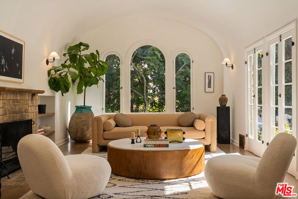 A hidden gem in the hills of Beachwood Canyon, this 1920s Spanish Revival home offers a warm, romantic elegance. Original architectural details include graceful curved windows and a dramatic Batchelder fireplace create an inviting sense of history. Natural light flows throughout, furnishing glimpses of the surrounding gardens and the canyon beyond. Vaulted ceilings add volume and airiness to the living spaces, while the three spacious bedrooms and two full baths provide comfortability. Thoughtful updates to the home offer modern convenience without compromising its period charm. This home blends timeless architecture with everyday comfort.Step outside and discover a private garden sanctuary, perfect for entertaining. Stunning Eden roses climb the exterior wall. A curated mix of mature olive trees, blooming jasmine, camellias, and a variety of citrus including orange, lemon, lime, and grapefruit wrap the property in year-round color and fragrance. Stone paths wind through lush plantings and lead to a small orchard where a fig trees joins the canopy evoking a sense of Mediterranean charm. The garden is replete with intimate moments, including a patio paved in salvaged 17th-century terracotta tiles, a quiet testament to timeless materials and old-world craftsmanship.Just minutes from both Franklin and Larchmont Villages, this is a rare opportunity to own a piece of Los Angeles history with enduring style and reserved sophistication.