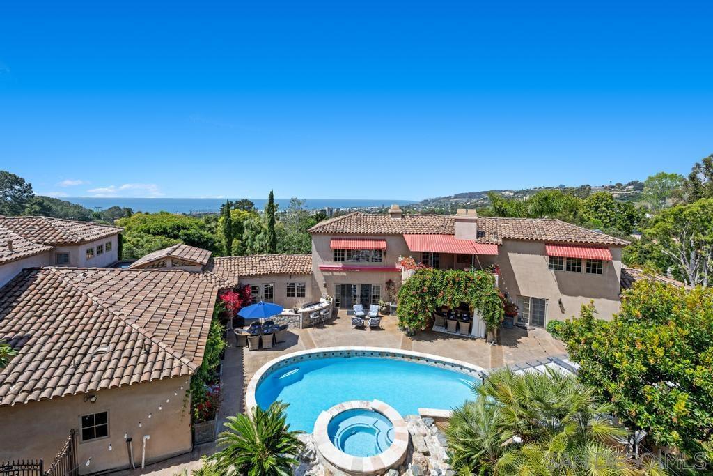 Welcome to this elegant, ivy-covered villa with grand architectural detail, enchanting gardens and panoramic ocean views. This palatial estate, perched in the rolling hills of La Jolla, is comprised of a luxurious main residence, attached guest house, a wellness pavilion, plus amenities that rival a 5-star resort. The property provides an unmatched experience of serenity and privacy, all just moments from the finest beaches and local attractions of La Jolla.As you pass through the stately gates, a meticulously paved driveway winds through immaculate gardens, leading to a grand stone fountain that signals the prestige of this remarkable property. The estate’s exterior is a study in timeless Mediterranean beauty, with terracotta roof tiles, wrought-iron balconies, and walls adorned with cascading ivy, creating a secluded haven that exudes charm and sophistication. Upon entering the main house, you are greeted by a magnificent foyer with soaring ceilings, an elegant fireplace, formal living room, and a sweeping staircase, setting the tone for the grandeur within. The gourmet kitchen is a chef’s dream, featuring exposed brick accents, vaulted ceilings with skylights, and a stunning oversized island. This space seamlessly flows into the intimate dining area, where seating for six is framed by custom windows that offer lush garden views. The adjacent family room invites relaxation, with a grand fireplace, plush sectional sofa, flatscreen TV, beverage storage refrigerator, and striking exposed beam ceilings that evoke a sense of rustic refinement. The primary suite is a true sanct As you pass through the stately gates, a meticulously paved driveway winds through immaculate gardens, leading to a grand stone fountain that signals the prestige of this remarkable property. The estate’s exterior is a study in timeless Mediterranean beauty, with terracotta roof tiles, wrought-iron balconies, and walls adorned with cascading ivy, creating a secluded haven that exudes charm and sophistication. Upon entering the main house, you are greeted by a magnificent foyer with soaring ceilings, an elegant fireplace, formal living room, and a sweeping staircase, setting the tone for the grandeur within. The gourmet kitchen is a chef’s dream, featuring exposed brick accents, vaulted ceilings with skylights, and a stunning oversized island. This space seamlessly flows into the intimate dining area, where seating for six is framed by custom windows that offer lush garden views. The adjacent family room invites relaxation, with a grand fireplace, plush sectional sofa, flatscreen TV, beverage storage refrigerator, and striking exposed beam ceilings that evoke a sense of rustic refinement. The primary suite is a true sanctuary, embodying the height of luxury with its cozy fireplace and an expansive private deck that overlooks the estate’s pristine grounds. The en-suite bathroom is a spa-like retreat, boasting a deep soaking tub, dual vanities, an opulent glass-enclosed rain shower, and a sprawling walk-in closet. Each of the three additional guest bedrooms are meticulously designed, offering both style and comfort, ensuring every guest enjoys the epitome of refined living. Step outside to a verdant resort-style backyard, where the natural beauty of the landscape blends effortlessly with high-end amenities. The sparkling pool and spa, complete with a cascading waterfall, serve as the centerpiece of this lush outdoor paradise. A shaded lounge area provides the perfect spot to unwind, while the covered alfresco dining space, featuring seating for six beside a grand outdoor fireplace, offers an unforgettable setting for evening meals under the stars. The outdoor chef’s kitchen, equipped with state-of-the-art appliances and a BBQ, is perfectly appointed for hosting superior gatherings. The estate’s 2,000 sq. ft. guest house offers its own brand of splendor, featuring exposed beam ceilings, a flowing open floor plan, and a sophisticated living area complete with...
