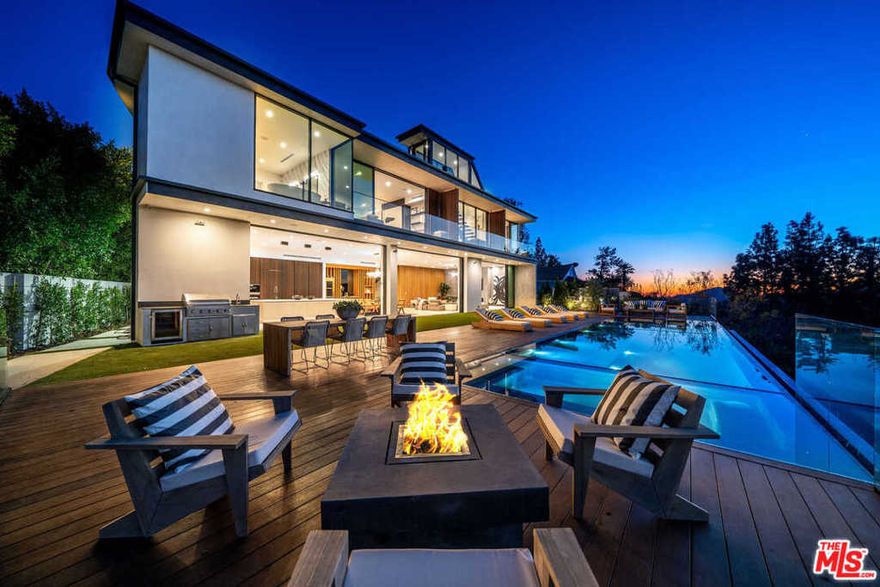 This stunning, contemporary new architectural captures panoramic canyon and mountain views from its hillside perch in Bel Air. Envisioned to reflect the natural surroundings, the 6,550-sq-ft home showcases an exquisite mix of glass, stone and wood, maximizing views from every room. Arrive to the magnificent entry hall with double-height ceilings and suspended wood and glass staircase. Open-plan living and dining areas include a custom wine display and Italian chefs kitchen with Miele appliances, quartz countertops and walk-in pantry. 12 Fleetwood pocket doors open to the 55 infinity pool/spa, fire pit and expansive terraces with jetliner views. 5 bedrooms include the exceptional master with terrace, walk-in dressing room and spa-style bath with tub and shower floating over the canyon. Melding masterful design and thoughtful amenities, the home boasts a rooftop terrace with fire pits and BBQ, home theater, office, 2nd-floor family room, Control4 Smart Home system and 2-car garage.