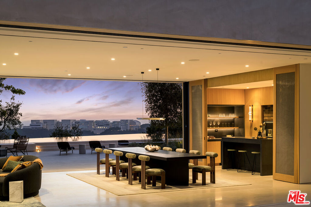 Nestled on 1.7 acres with 230 ft. of frontage sits this simply exquisite new construction architectural created by acclaimed Masastudio noted for its design of Amangiri Resort and Spa, enveloped by 180-degree views of the Getty Museum, ocean, Century City, Santa Monica, and lush mountain vistas, with no neighbors across the street. Spanning approx. 15,023 sq. ft., this 8-bedroom and 11-bath estate has been artfully designed with a harmonious triangular layout, featuring three expansive wings all wrapped around an outdoor center courtyard for an inviting and seamless blend of elegance and functionality. A magnificent kitchen with enormous island, all opening with expansive pocket windows to a large covered/heated lounge for 30 guests, overlooking the Getty and pool, to create the perfect setting for poolside barbecues or sipping wine into the evening. The principal sanctuary suite spans 3,400 sq. ft. with an expansive art corridor, main bedroom area with fireplace, private deck and balcony, two full baths, and walk-in closets connected by a concrete black iron finish soaking tub and floor-to-ceiling walls of glass, allowing for lush treetop views. A large private office/den at one end of the principal suite includes a wet bar and private elevator landing, just outside the primary entry door and separate office door. You'll also find a family corridor with 3 suites and upper family room with incredible views. Separate upper-level guest wing with 2 suites, full kitchen, family room, dining area, laundry room, and private elevator from the garage foyer below. The main floor features 2 beautiful guest suites with immediate access to the grassy wraparound lawns from each side of the estate. Swiss state-of-the-art automated doors and windows by the company, Panoramah, throughout. A grand main staircase ascends to the second floor, with a dramatic triangular skylight landing and a large wall-to-wall additional panorama window frames the stunning views with beams of light. Family theater with kitchenette and corner lounge, and gym with explosive Getty views and large grassy walk-out living and sitting areas are also found on both sides. An artful triangular-shaped infinity pool with an integrated 60 ft. swimmer's lane, oversized spa, and Baja with waterfalls complete this resort home, along with a large second-floor entertaining deck, creating an atmosphere of timeless luxury. Savant Smart Home, 3 laundry rooms, 2 elevators, large outer circular motor court, and gated parking for 8 cars, plus an oversized deep 4-car garage and security house. Architecture meets functionality with stunning views from every room in the house!