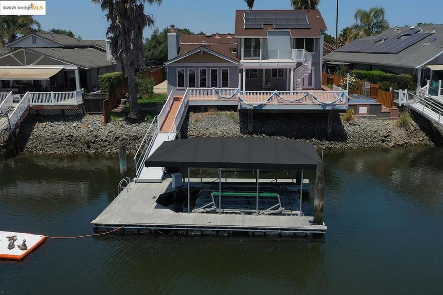 Beautiful remodeled waterfront home in a PRIME location with OWNED SOLAR! This home is just minutes from fast water and the marina, making it ideal for water enthusiasts. The property boasts a private dock and hoist, ensuring easy access to the waterways. The updated kitchen is designed for both functionality and elegance, equipped with modern appliances and finishes that cater to the culinary enthusiast. The bathrooms have been thoughtfully updated, providing a spa-like experience with contemporary fixtures and design.  The large primary suite serves as a tranquil retreat, complete with a relaxation area perfect for unwinding after a long day. Step out onto the deck from the primary suite and enjoy the serene views, with a circular stairway leading down to the main deck area. This home is designed for entertaining, offering separate areas that allow for intimate gatherings or larger celebrations.   Natural light floods the interior, creating a warm and inviting atmosphere throughout.  Off-street and trailer parking provide convenience and ease for residents and guests alike. Long water views enhance the property's appeal, offering a picturesque backdrop for daily living.