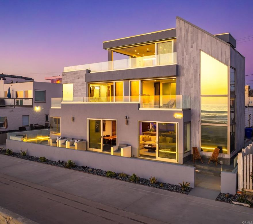 Perfectly positioned on the coveted front row of Mission Beach, this fully reimagined architectural residence captures panoramic ocean views from every level, offering a lifestyle defined by beachfront elegance, thoughtful design, and seamless indoor–outdoor living. Spanning three levels of striking industrial-modern detail, the home is wrapped in floor-to-ceiling sliding glass doors that bring the Pacific into every moment of the day. The main level welcomes you with an open-concept layout anchored by a bespoke chef’s kitchen, featuring a 5-burner range with direct ocean views and a sleek waterfall island. The living and dining areas flow effortlessly to a private ocean-facing patio, where an eight-person hot tub and multiple lounge spaces create a dynamic setting for hosting and relaxation just steps from the boardwalk. The second floor is home to the primary suite, a private retreat with its own ocean-view balcony, freestanding soaking tub positioned for sunset views, curbless walk-in shower, and dual vanities—all finished in refined, spa-like detail. This level also includes two additional bedrooms, two full bathrooms, and a convenient laundry room, offering both function and flexibility for guests or family. The top floor unfolds into a dramatic entertainer’s loft—an indoor-outdoor pavilion where walls of glass vanish, connecting the interior to a sweeping wraparound terrace. With expansive lounge areas and unobstructed coastal vistas, it’s a space designed for effortless gatherings, quiet mornings, and evenings defined by the rhythm of the waves. Designer coastal furnishings, hand-selected to complement the home’s architectural sensibility, are included in the sale. Engineered for coastal living, the home features marine-grade concrete and impact-resistant glass for strength and durability. A fully integrated smart-home system controls lighting, HVAC, audio, and security with ease, while curated accent lighting and backlit hallways set a distinct tone from day to night. Offering a rare level of privacy for a front-row location, the home is flanked by alleyways on both sides, creating a unique sense of space and separation seldom found on the Mission Beach boardwalk. With a two-car garage and two additional off-street spaces, parking is abundant—another rare amenity for this setting. Situated at the intersection of vibrant beach life and elevated design, this extraordinary residence invites you to experience San Diego’s coastline at its most refined.